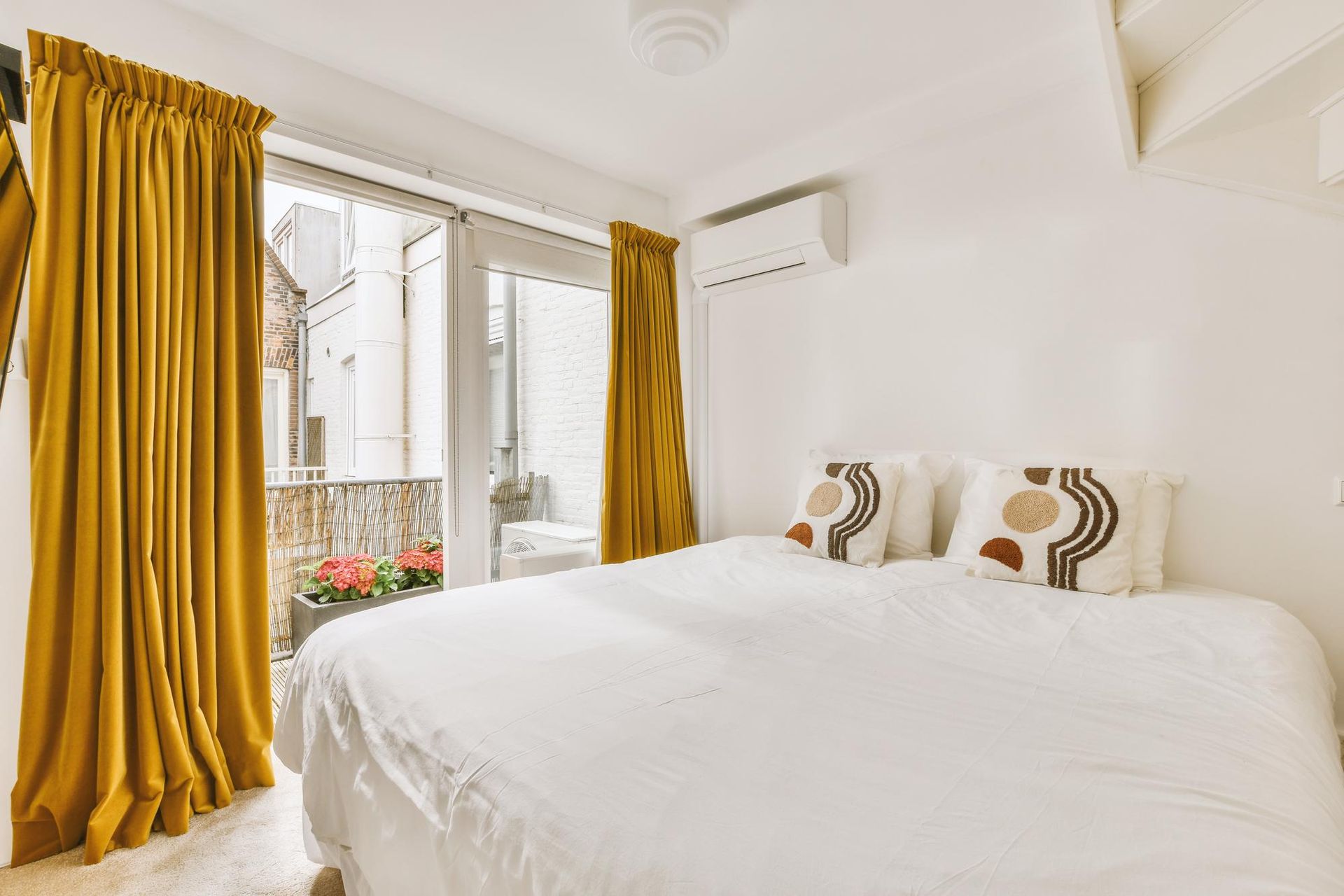 A bedroom with a bed , yellow curtains and a balcony.