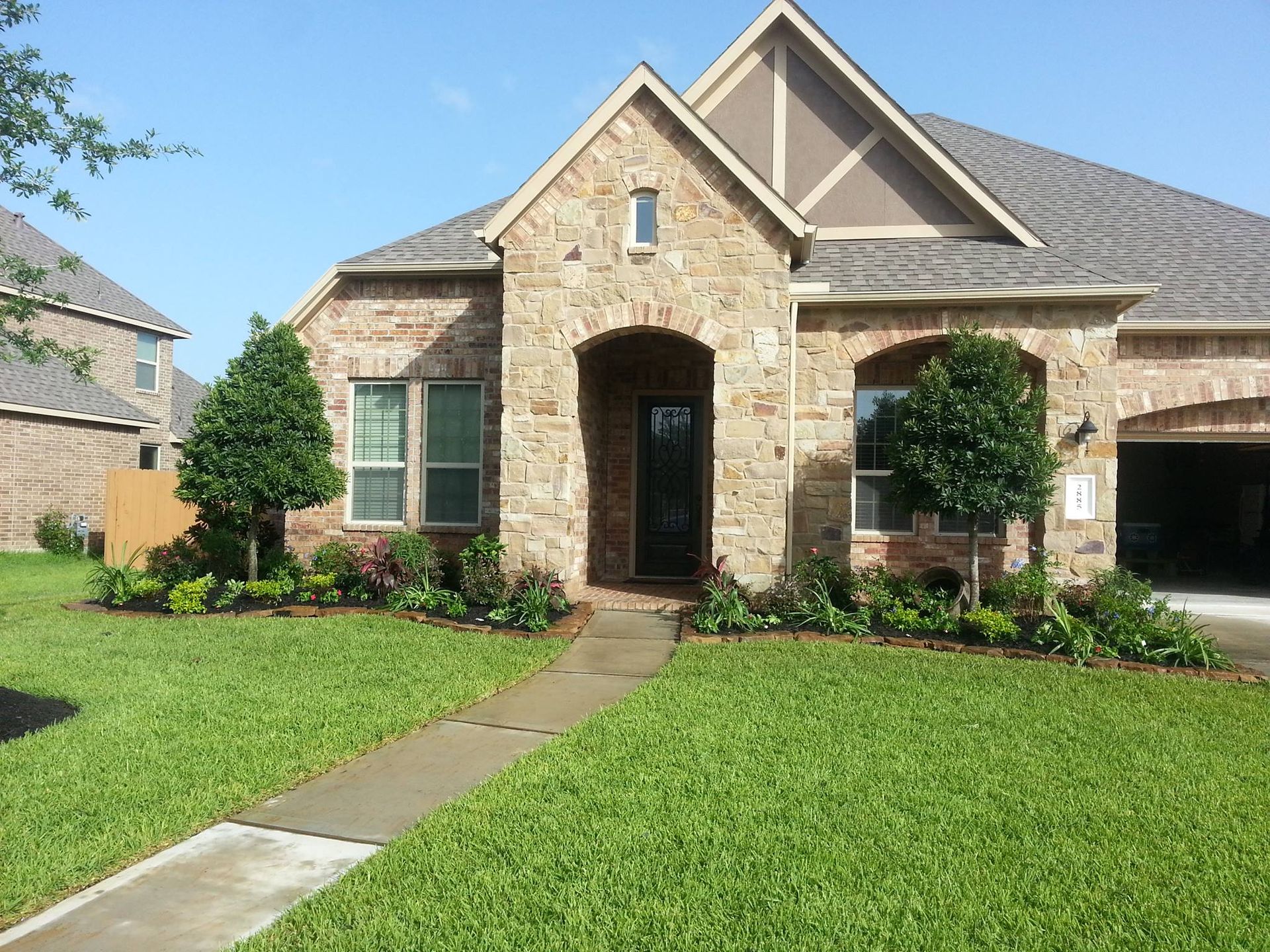A brick house with a lush green lawn in front of it