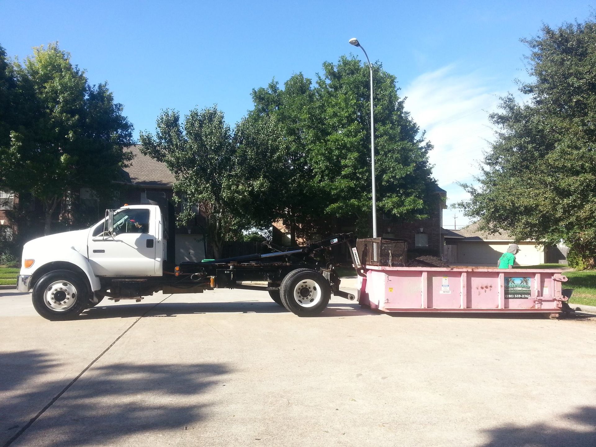 A white truck with a pink dumpster attached to it