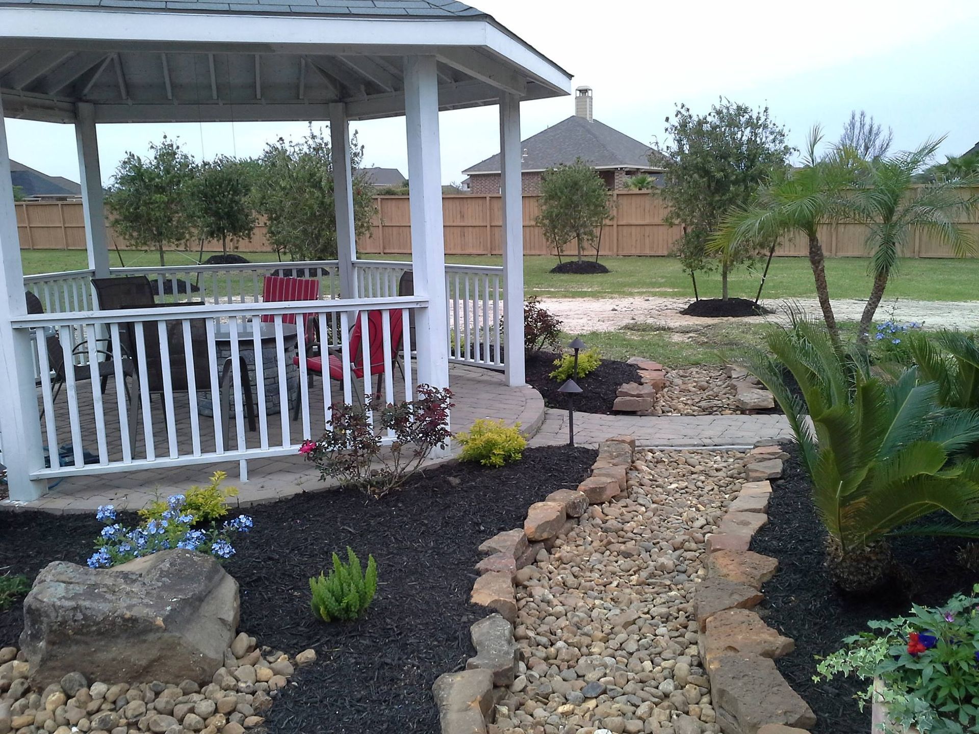 A gazebo with a white railing is in the middle of a garden