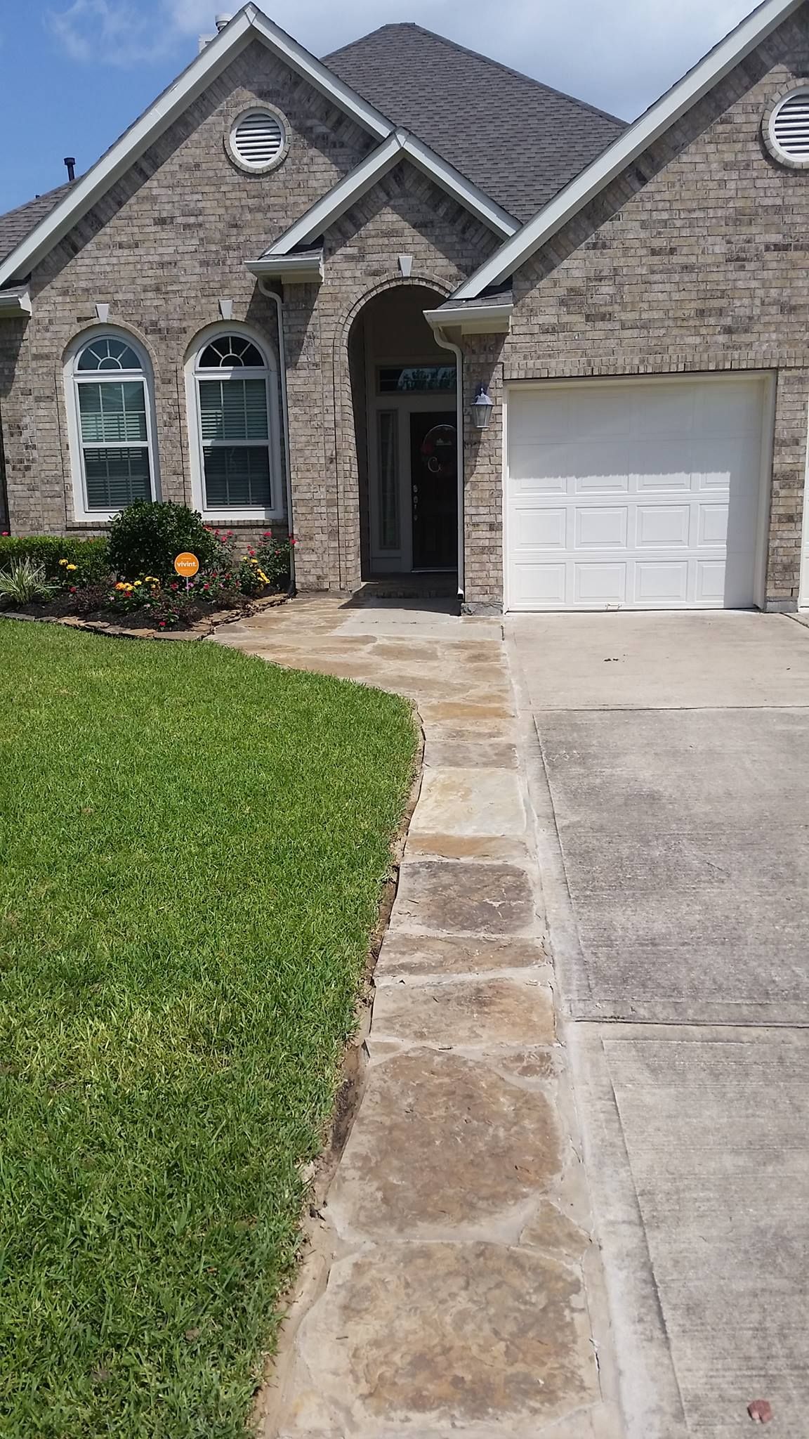 A brick house with a white garage door and a walkway leading to it.