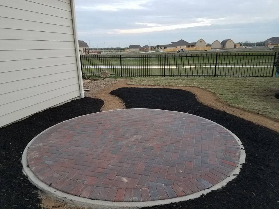 A circular brick patio with a fence in the background