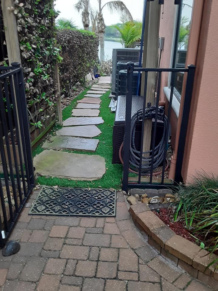 A brick walkway leading to a house with a hose hanging on the side of it.