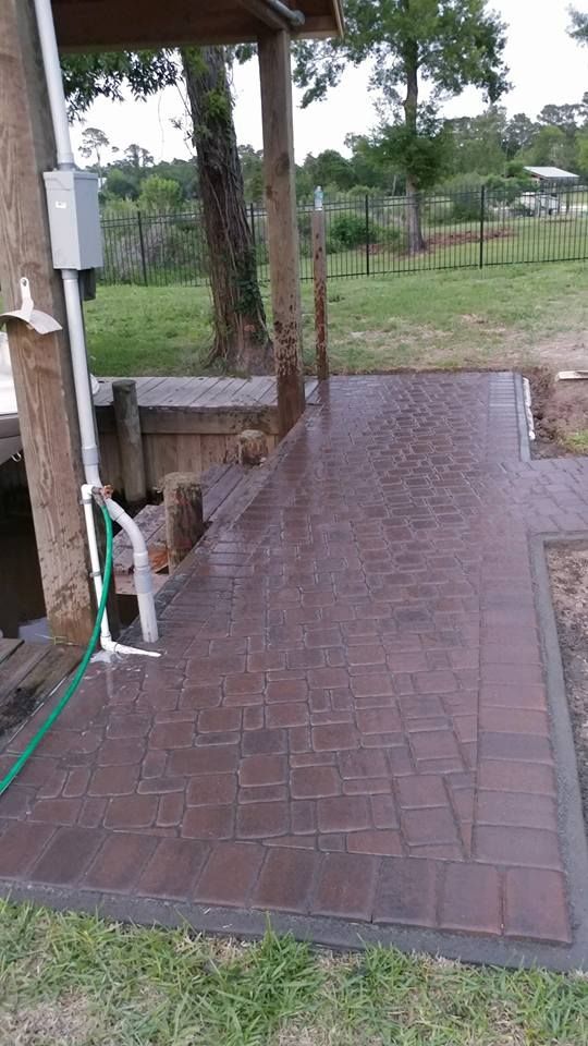 A brick patio with a green hose attached to it.