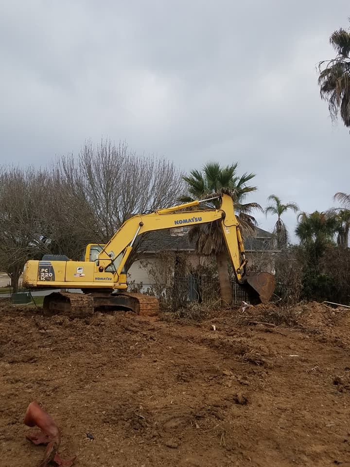 A yellow excavator is sitting in the middle of a dirt field.
