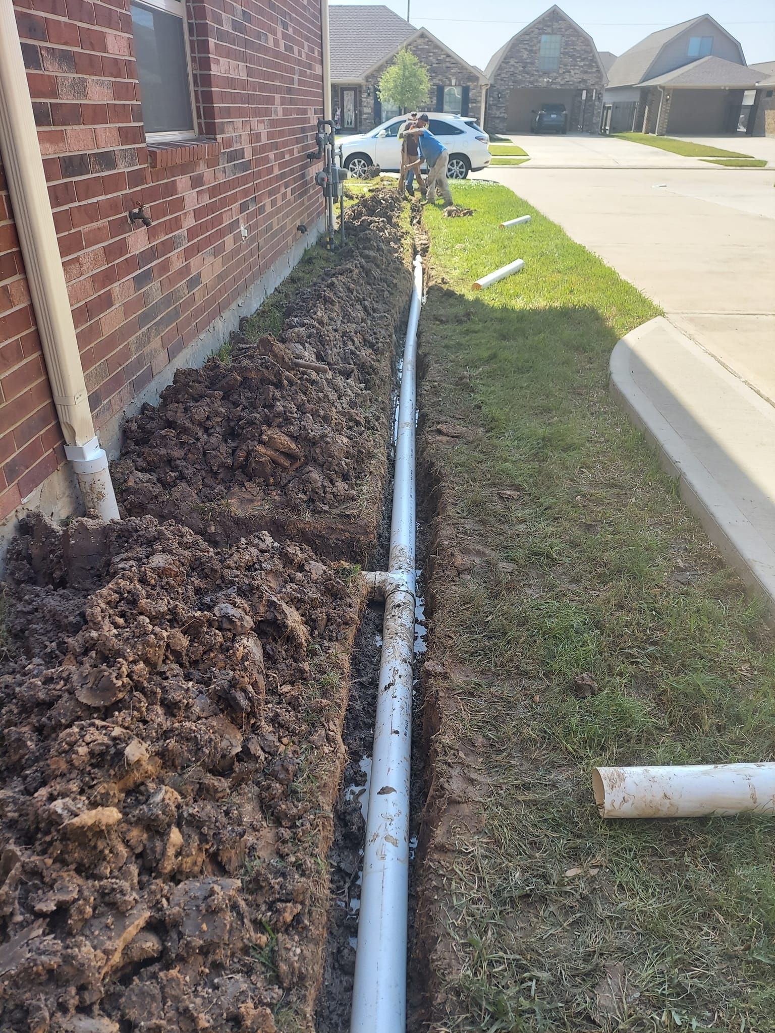 A drain pipe is being installed on the side of a house.