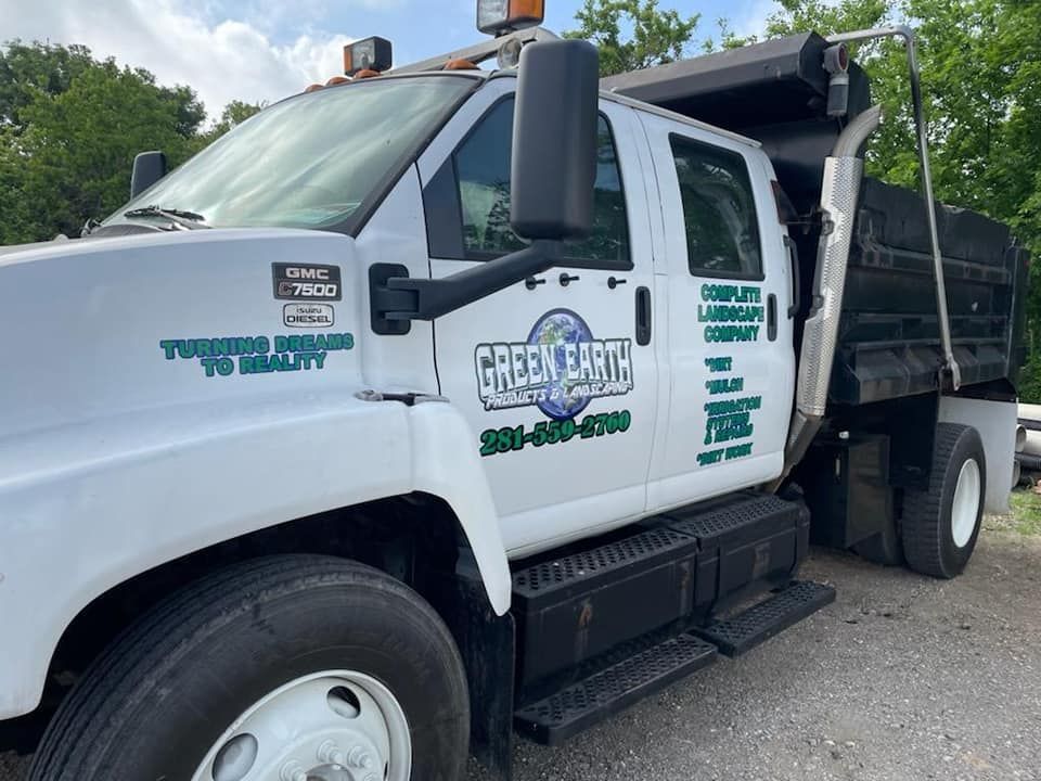 A white dump truck is parked on the side of the road.