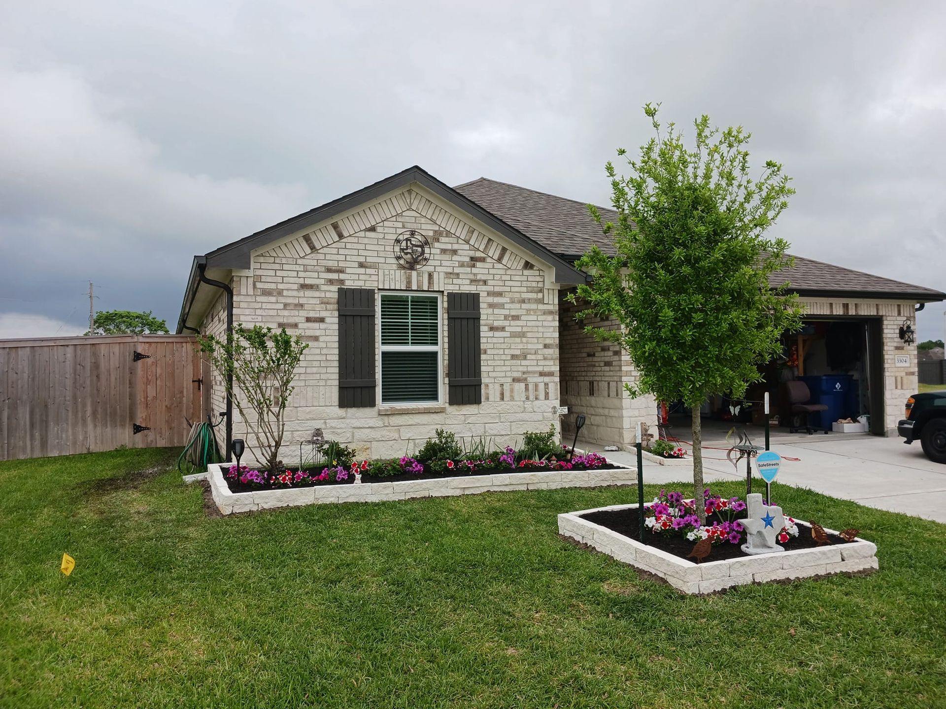 A house with a lot of grass and flowers in front of it.