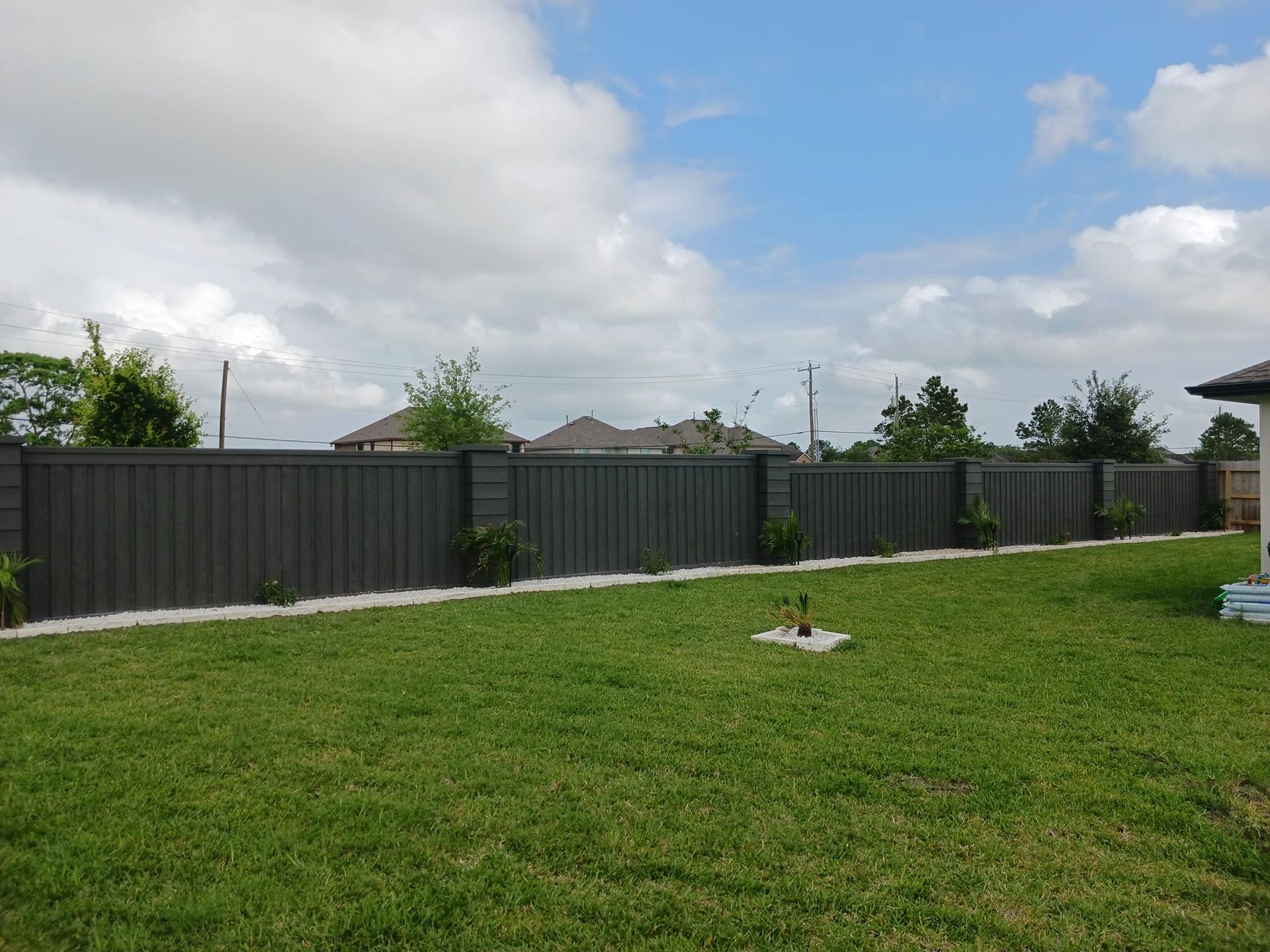 A backyard with a fence and a lush green lawn.