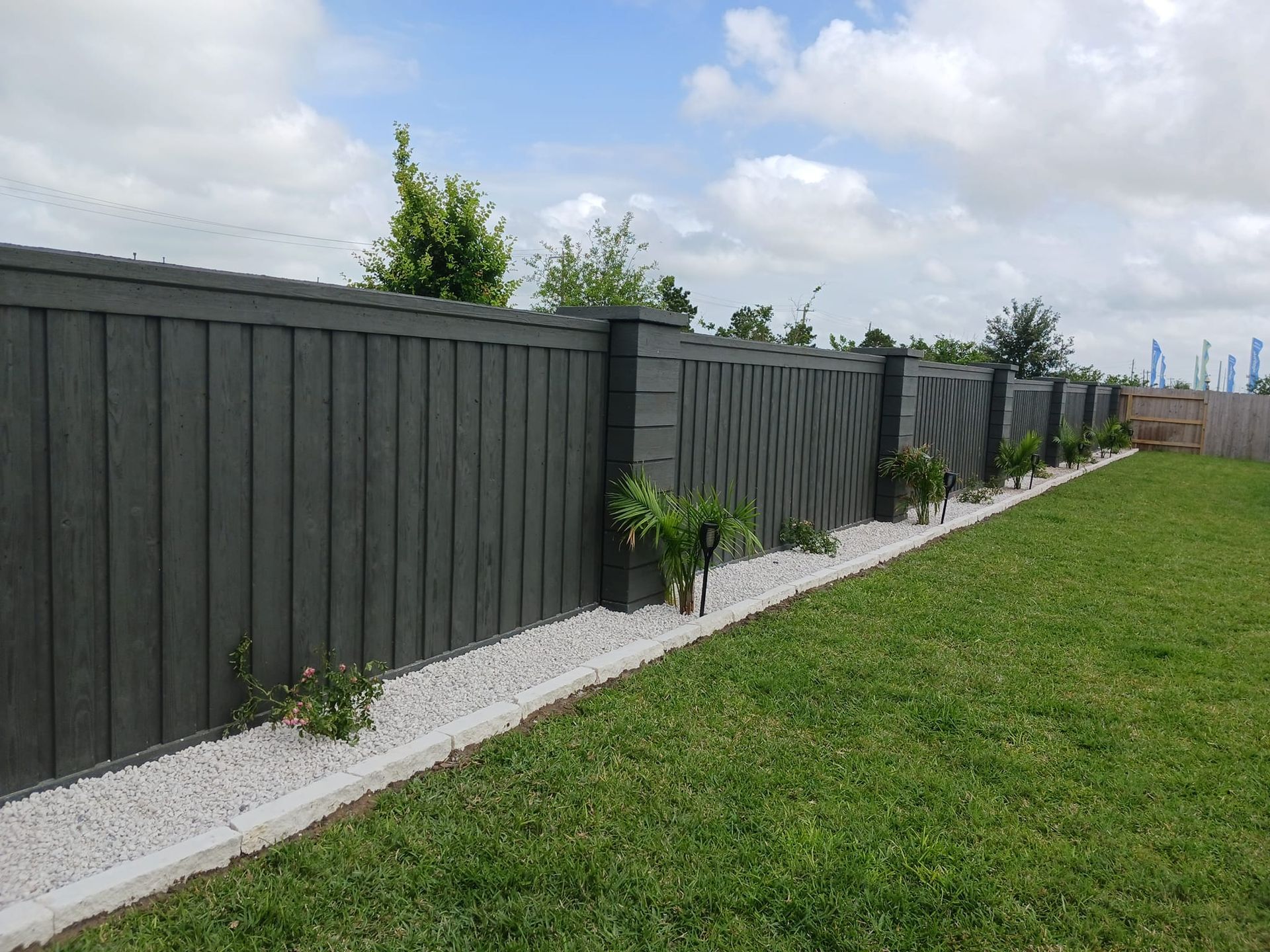 A black fence surrounds a lush green yard.