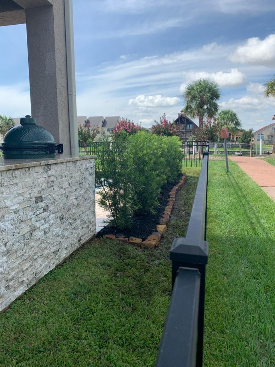A black fence surrounds a lush green yard.