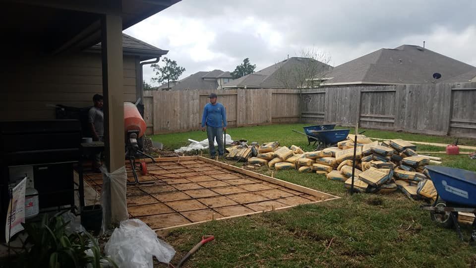 A man is standing in a backyard next to a pile of concrete.