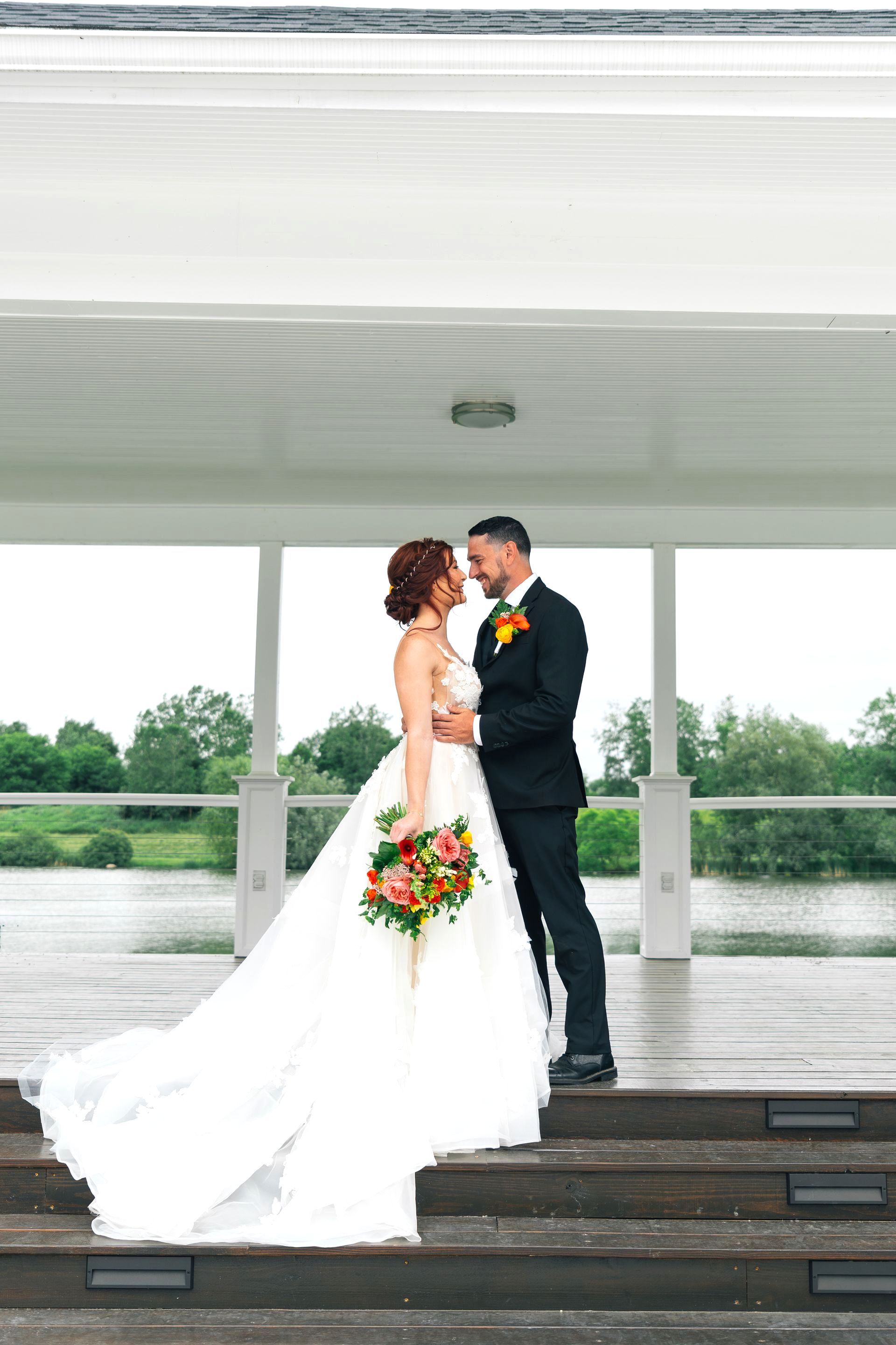 A bride and groom are standing on a set of stairs looking at each other.