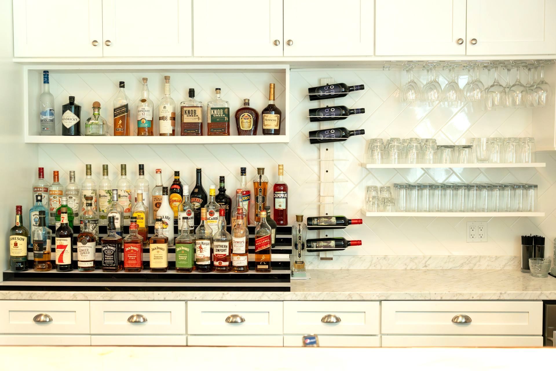 A bar with bottles of liquor and wine glasses on shelves.