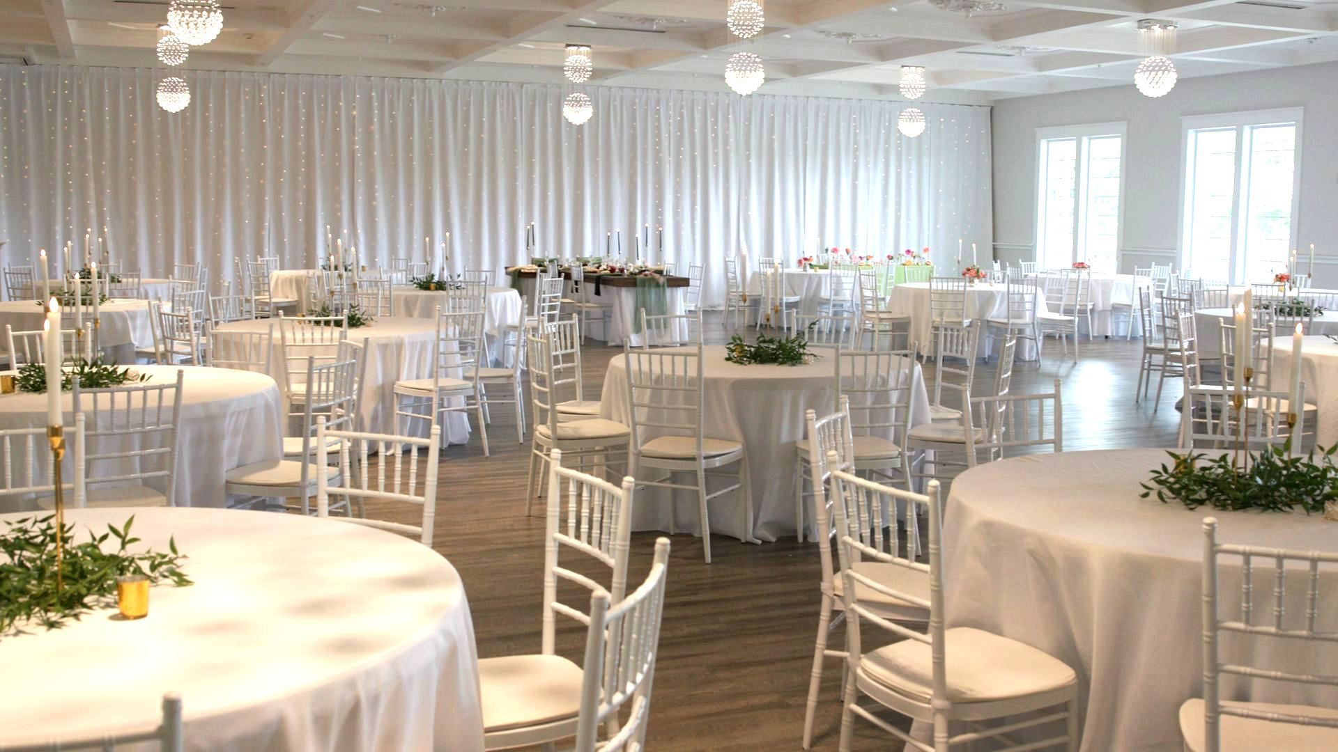 A large room with tables and chairs set up for a wedding reception.