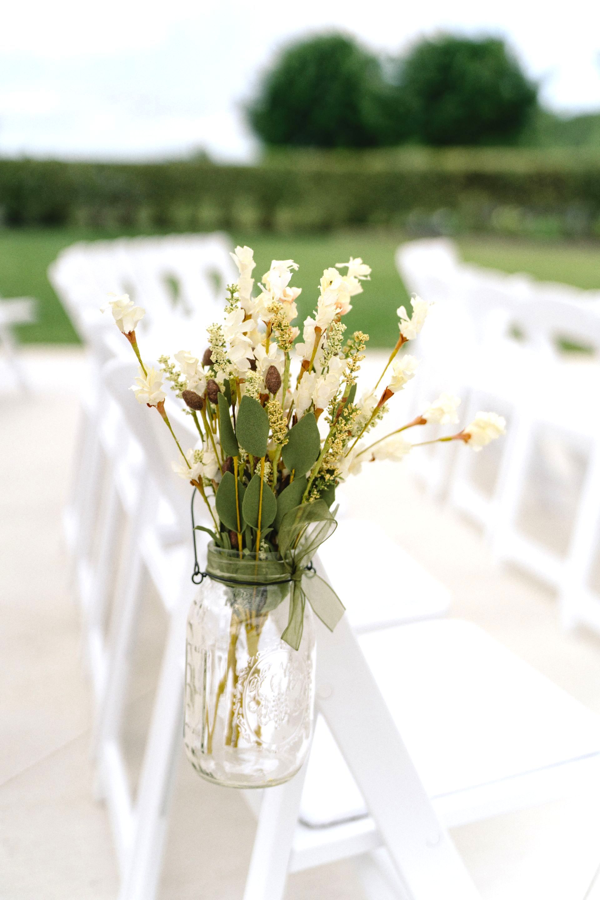 A mason jar filled with flowers is hanging on a chair