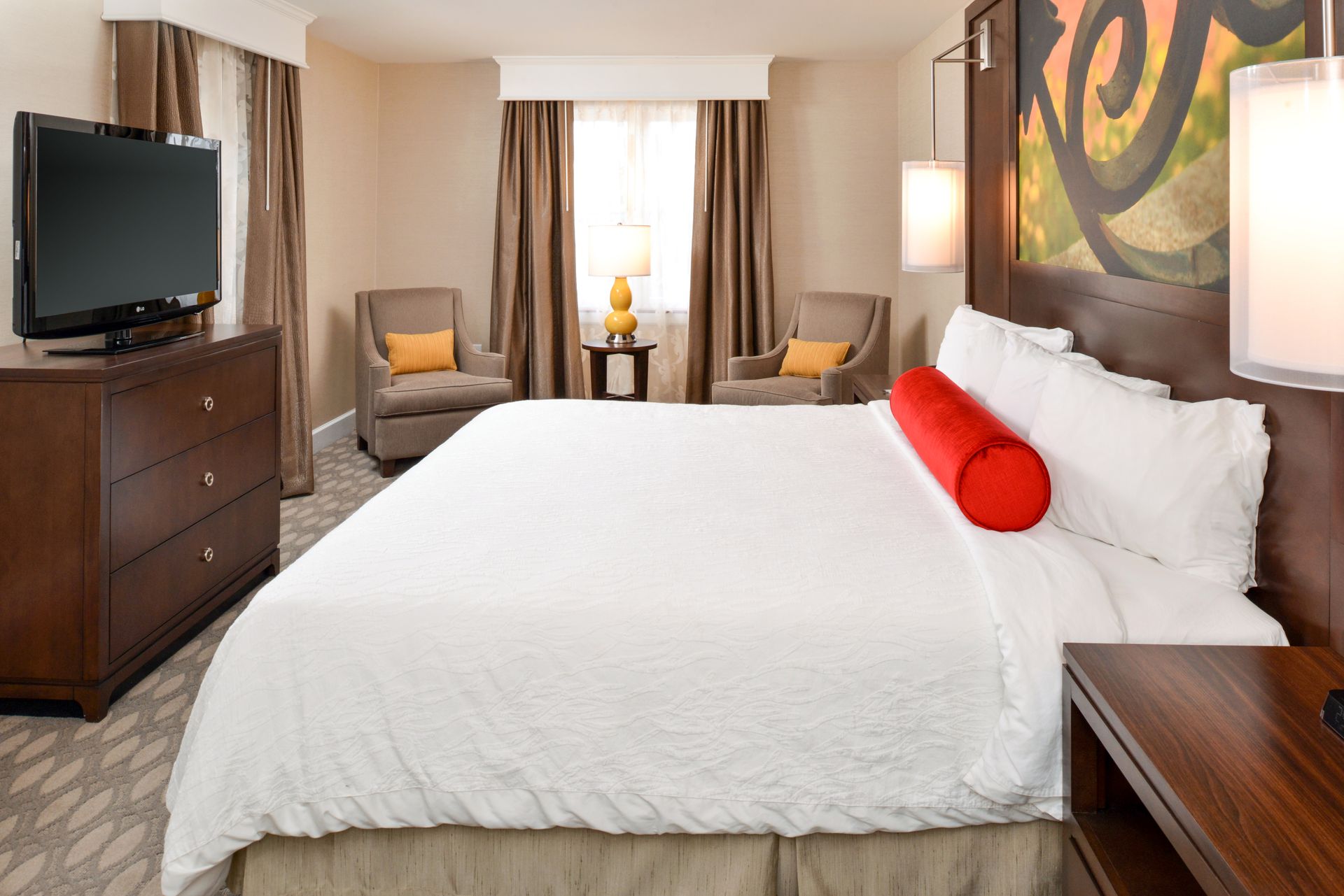 A hotel room with a king size bed and a flat screen tv