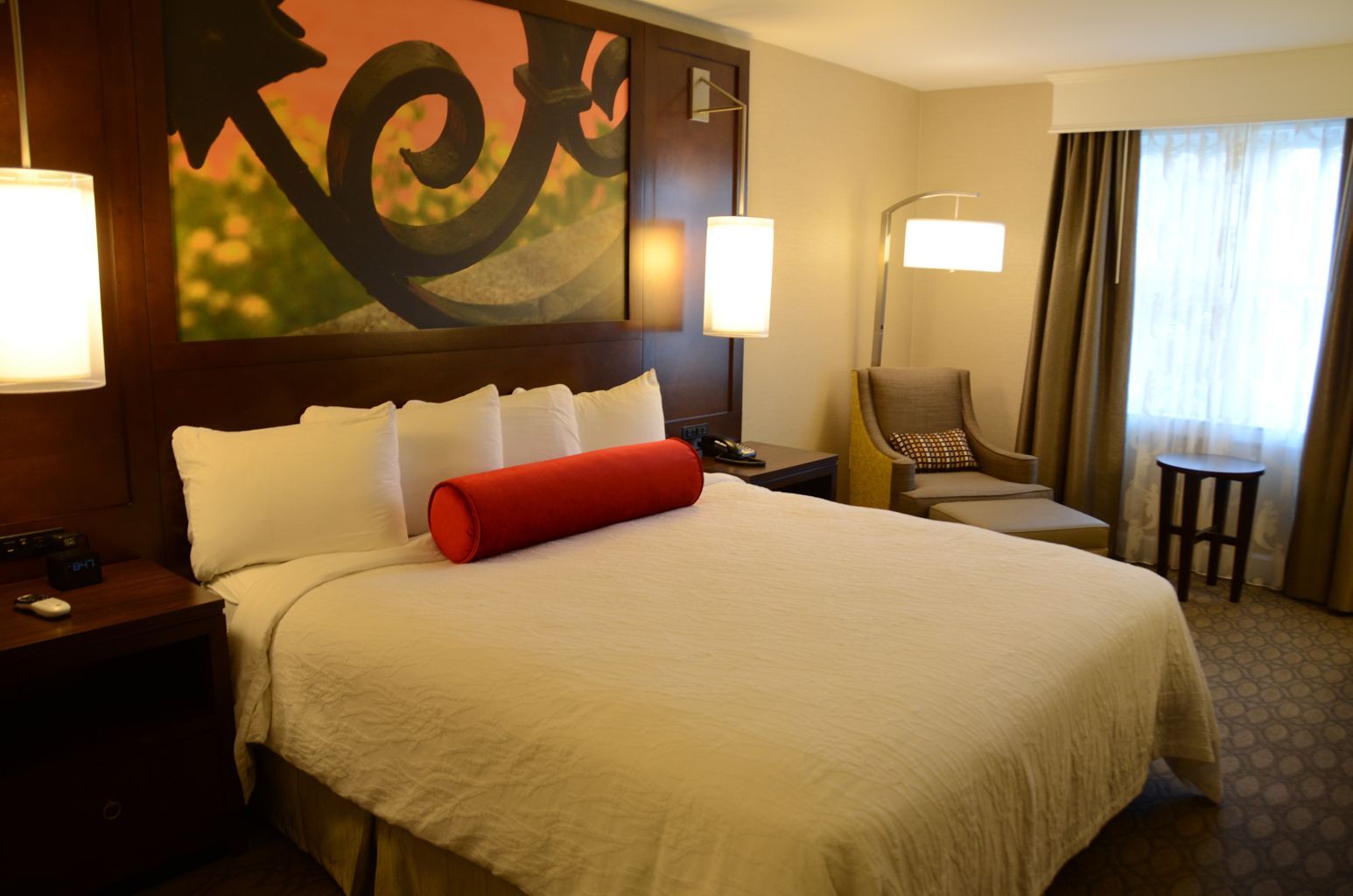 A hotel room with a king size bed and a chair