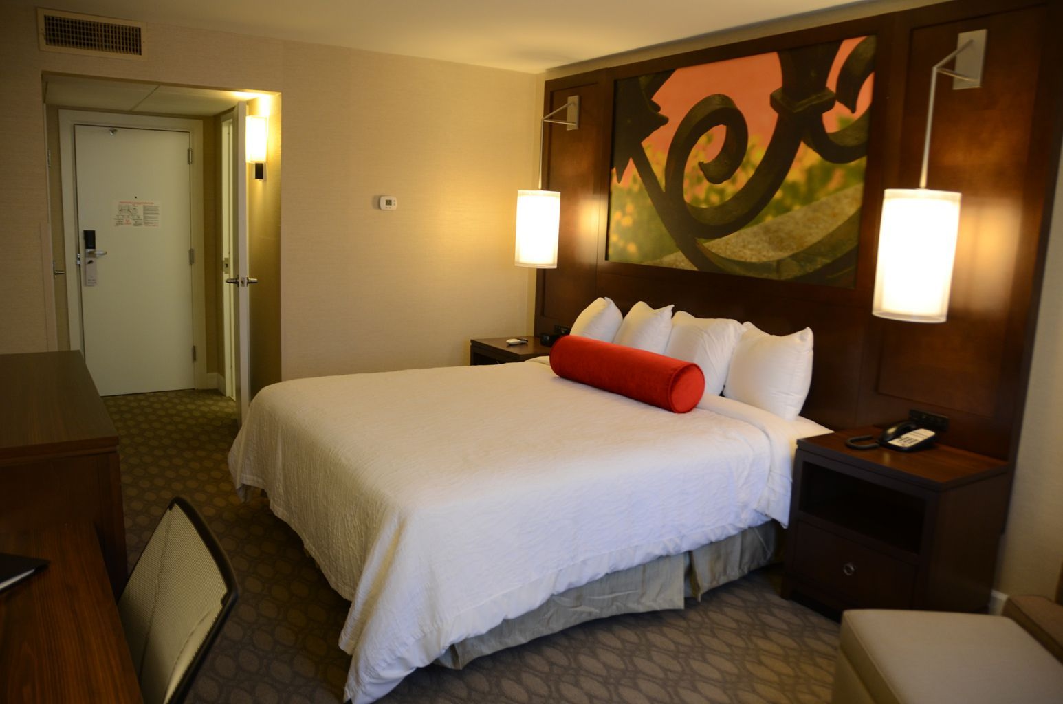 A hotel room with a large bed and a painting on the wall