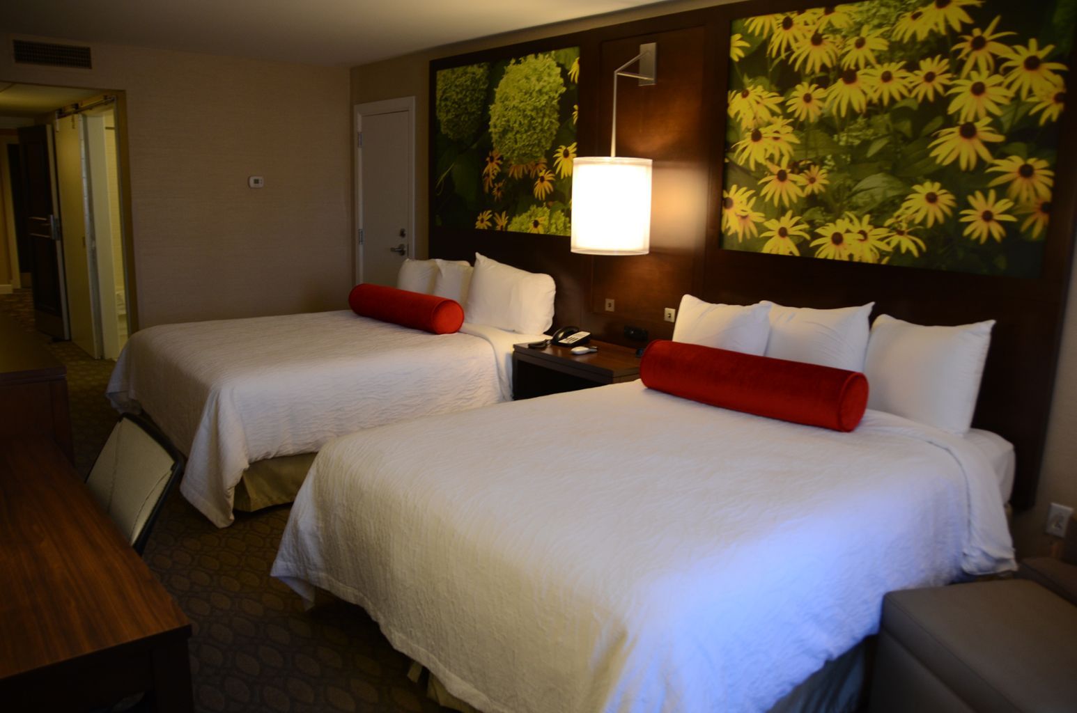 A hotel room with two beds and a painting on the wall