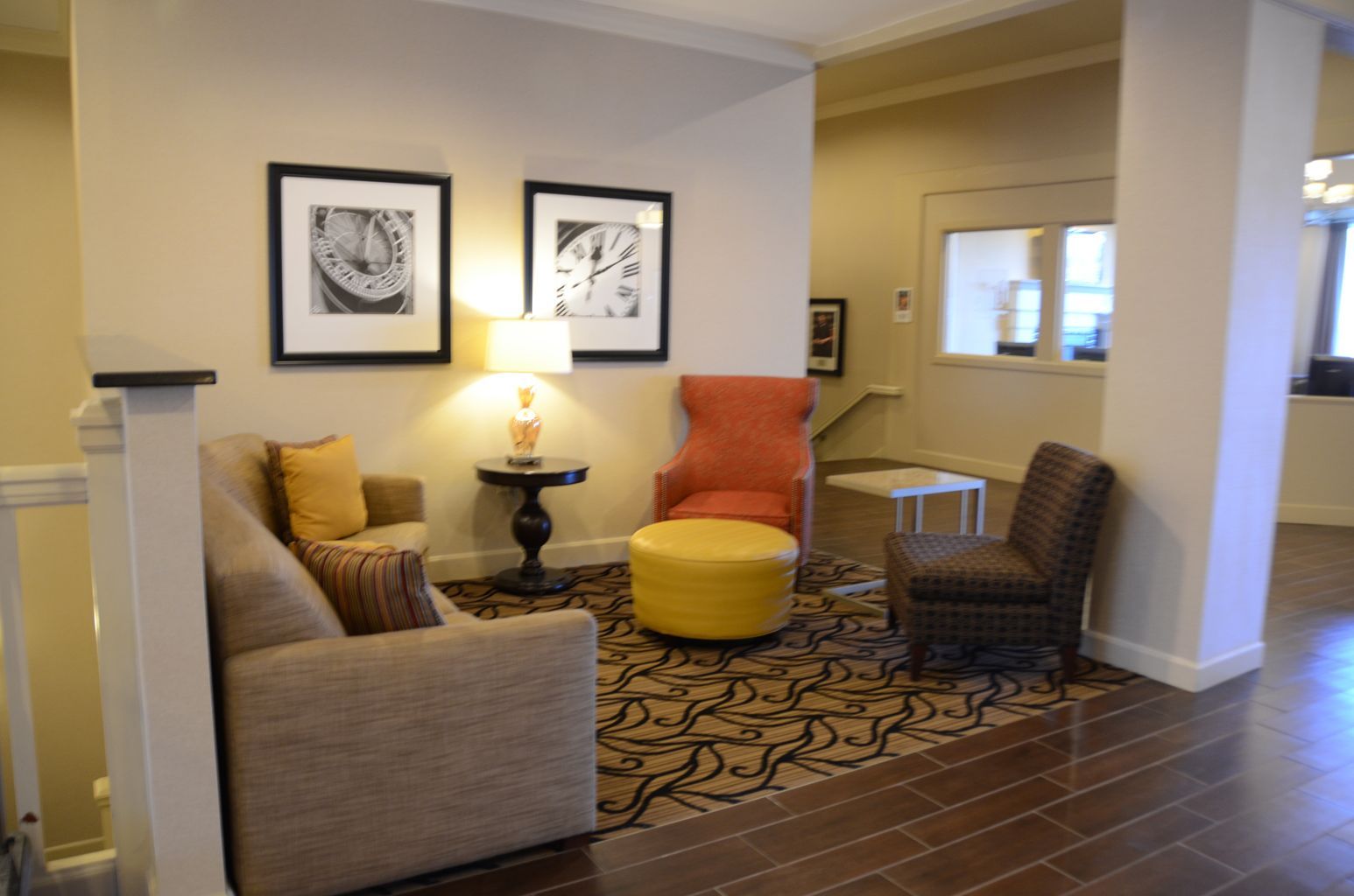 A living room with a couch , chairs , ottoman and lamps.