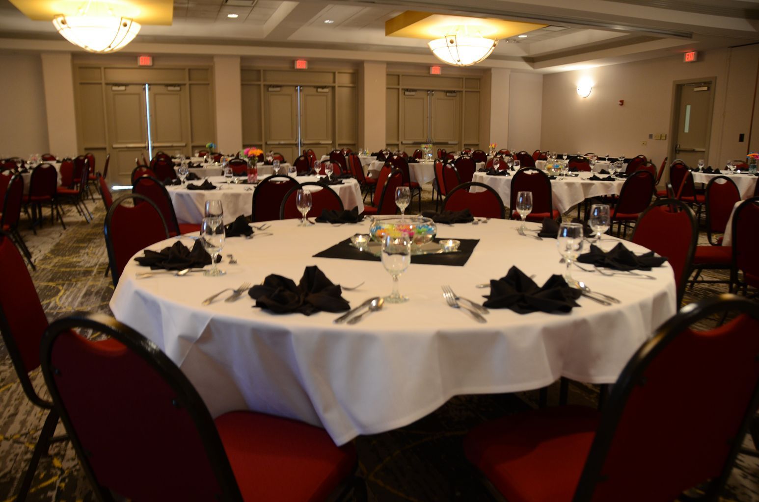 A large room with tables and chairs set up for a wedding reception.