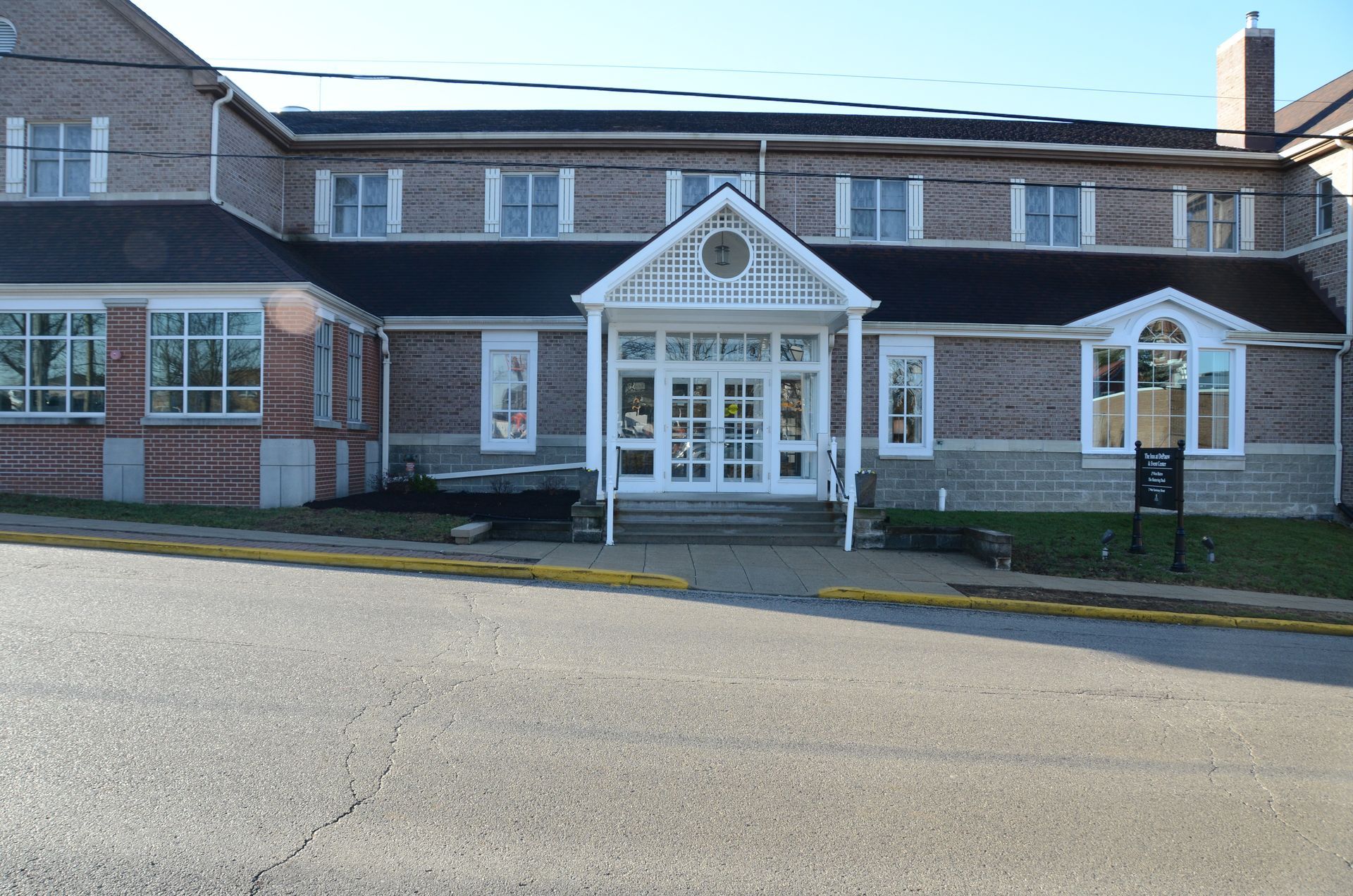 A large brick building with a white porch and stairs