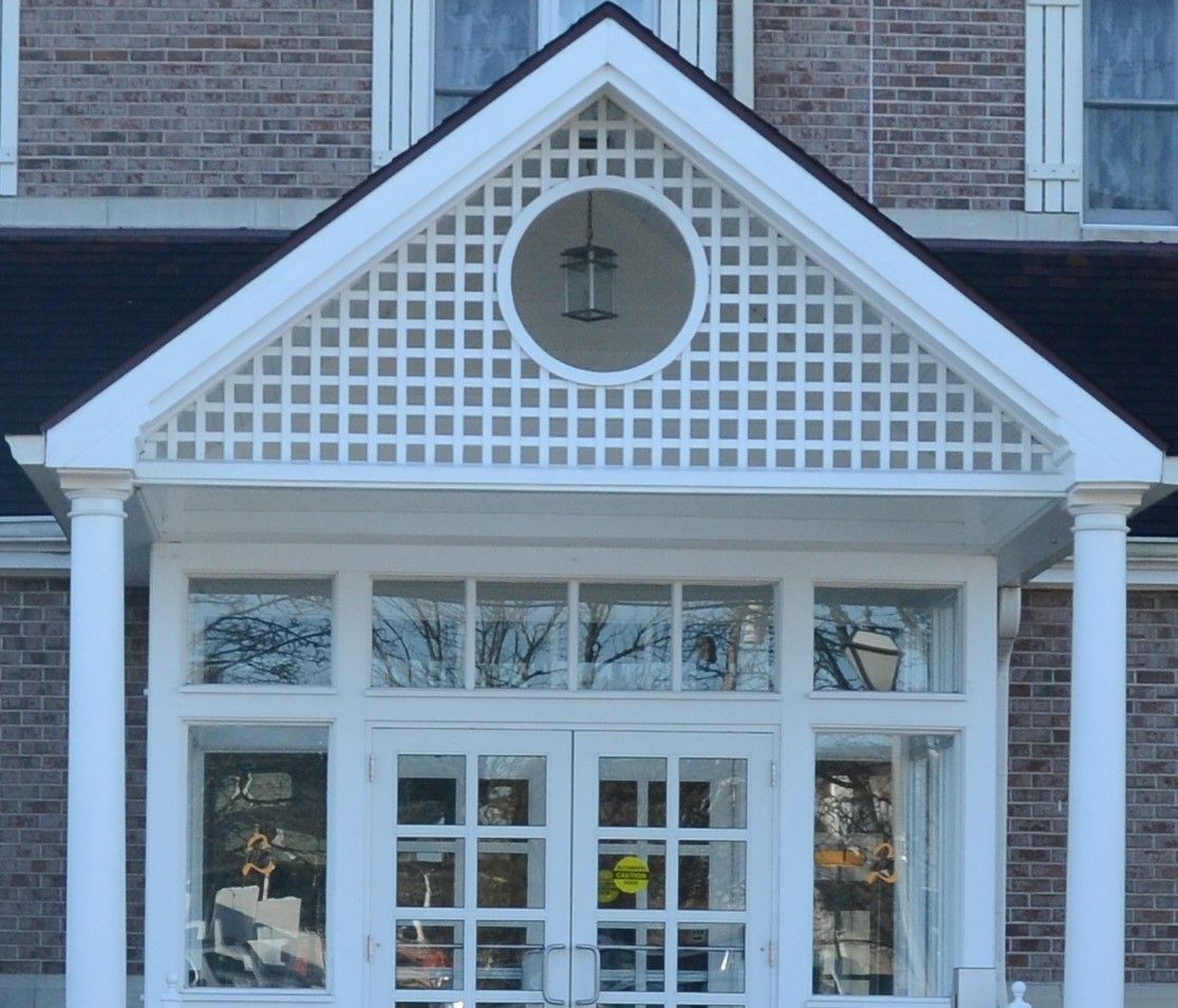 The front door of a brick building with a white porch