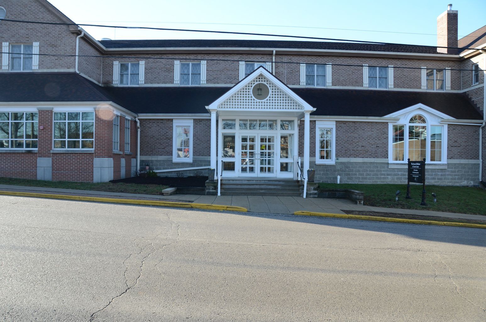 A large brick building with a white porch and stairs