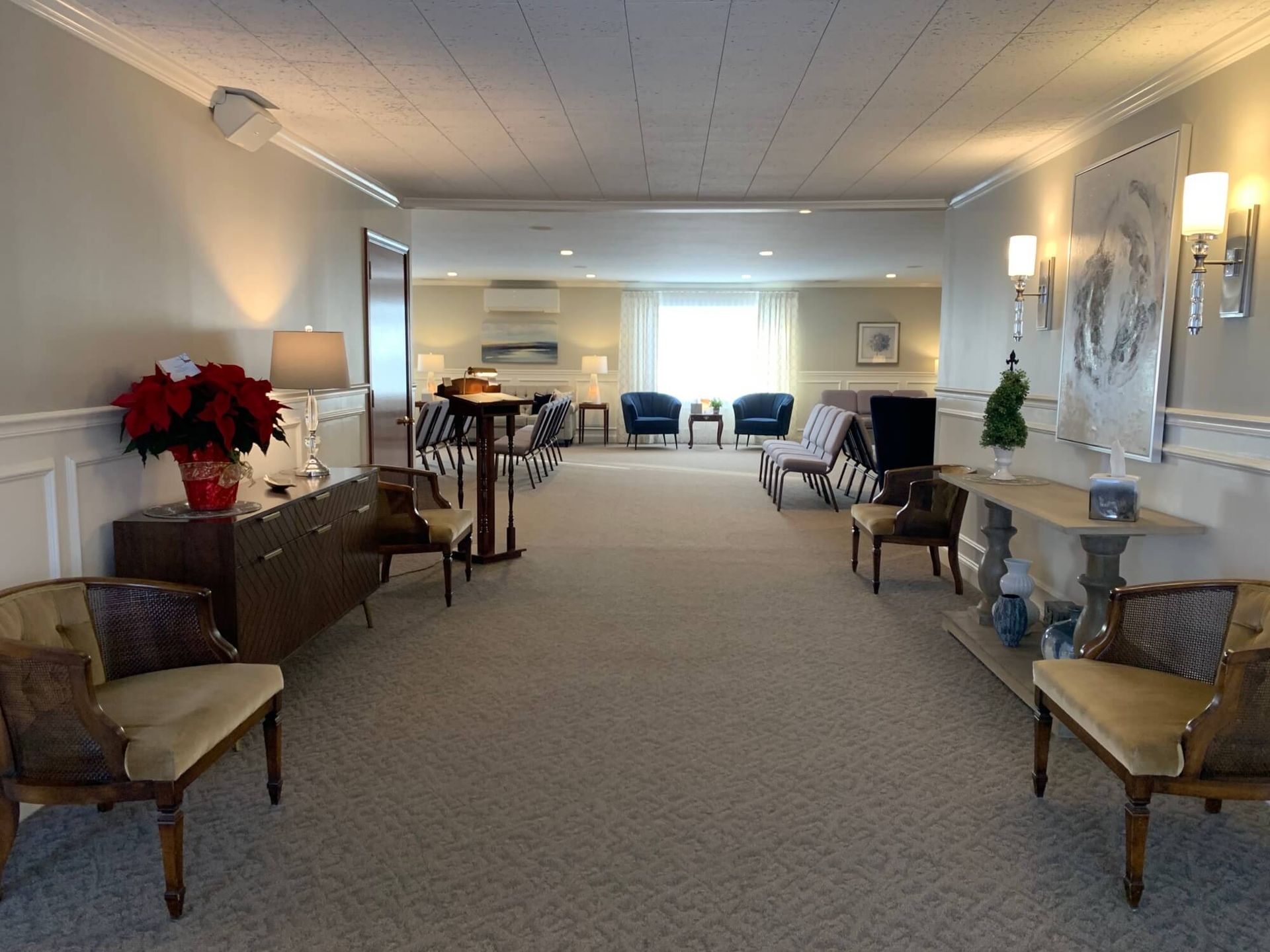 A long hallway with chairs and a table in a funeral home.