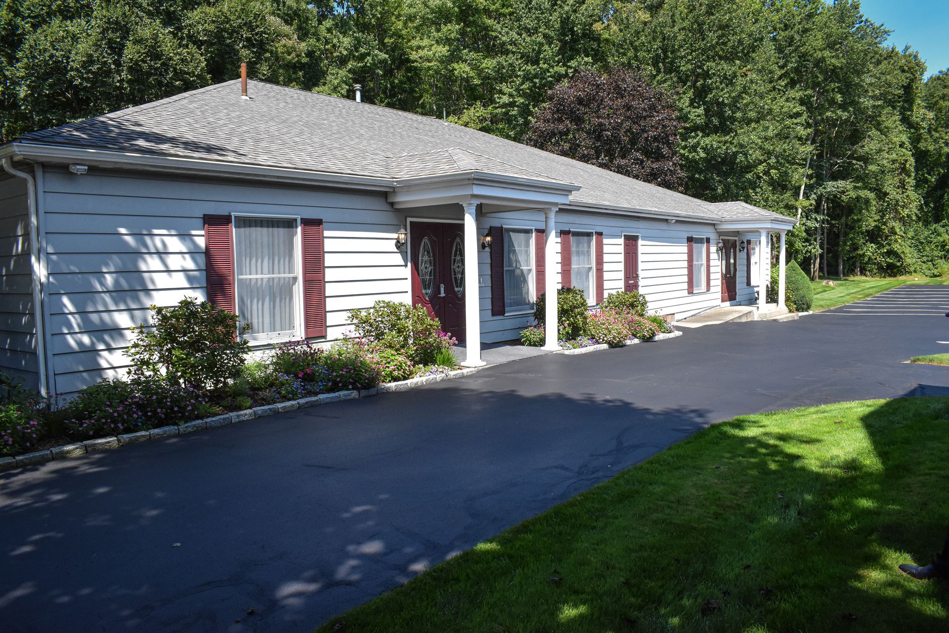 A white house with red shutters and a black driveway