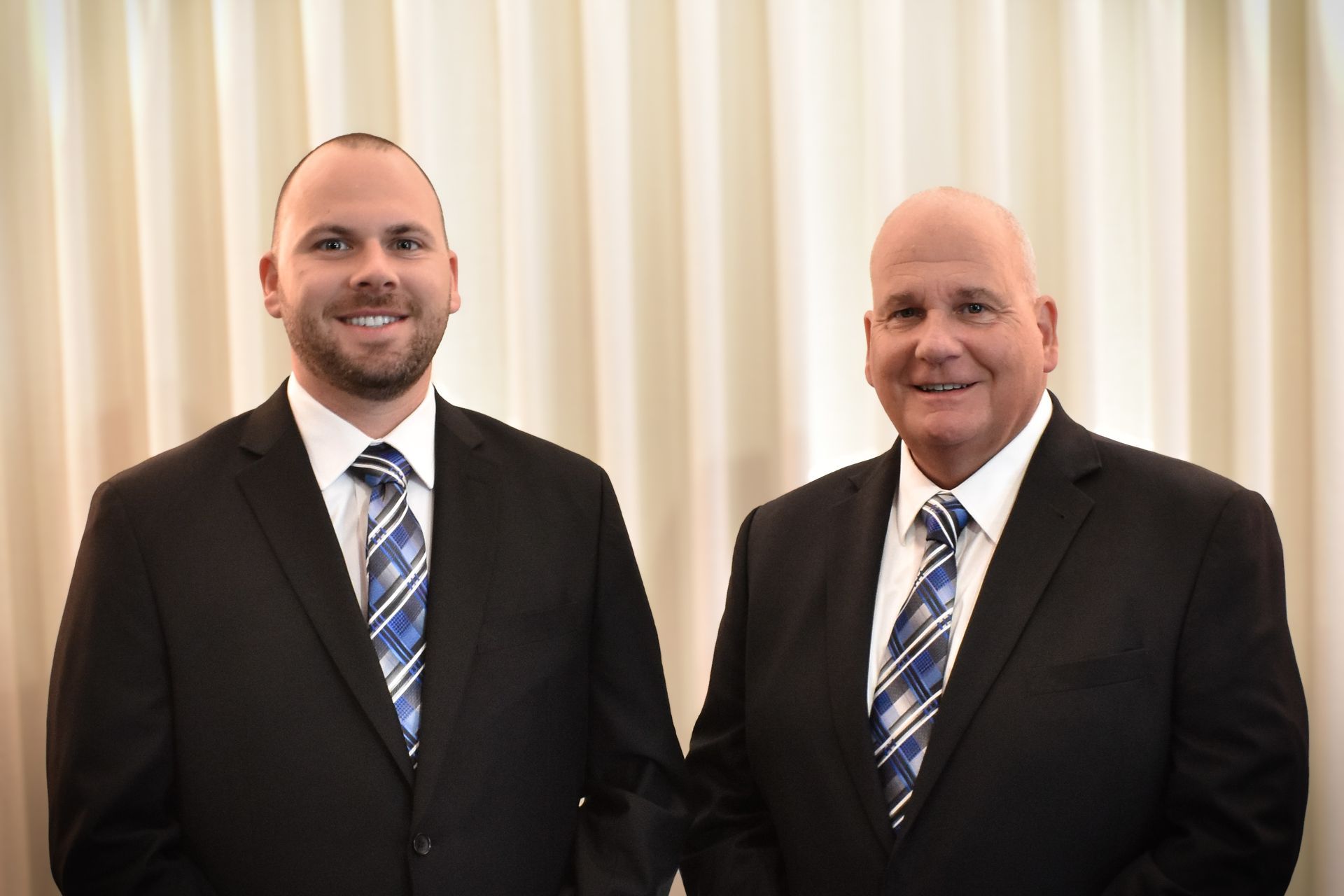 Two men in suits and ties are standing next to each other.