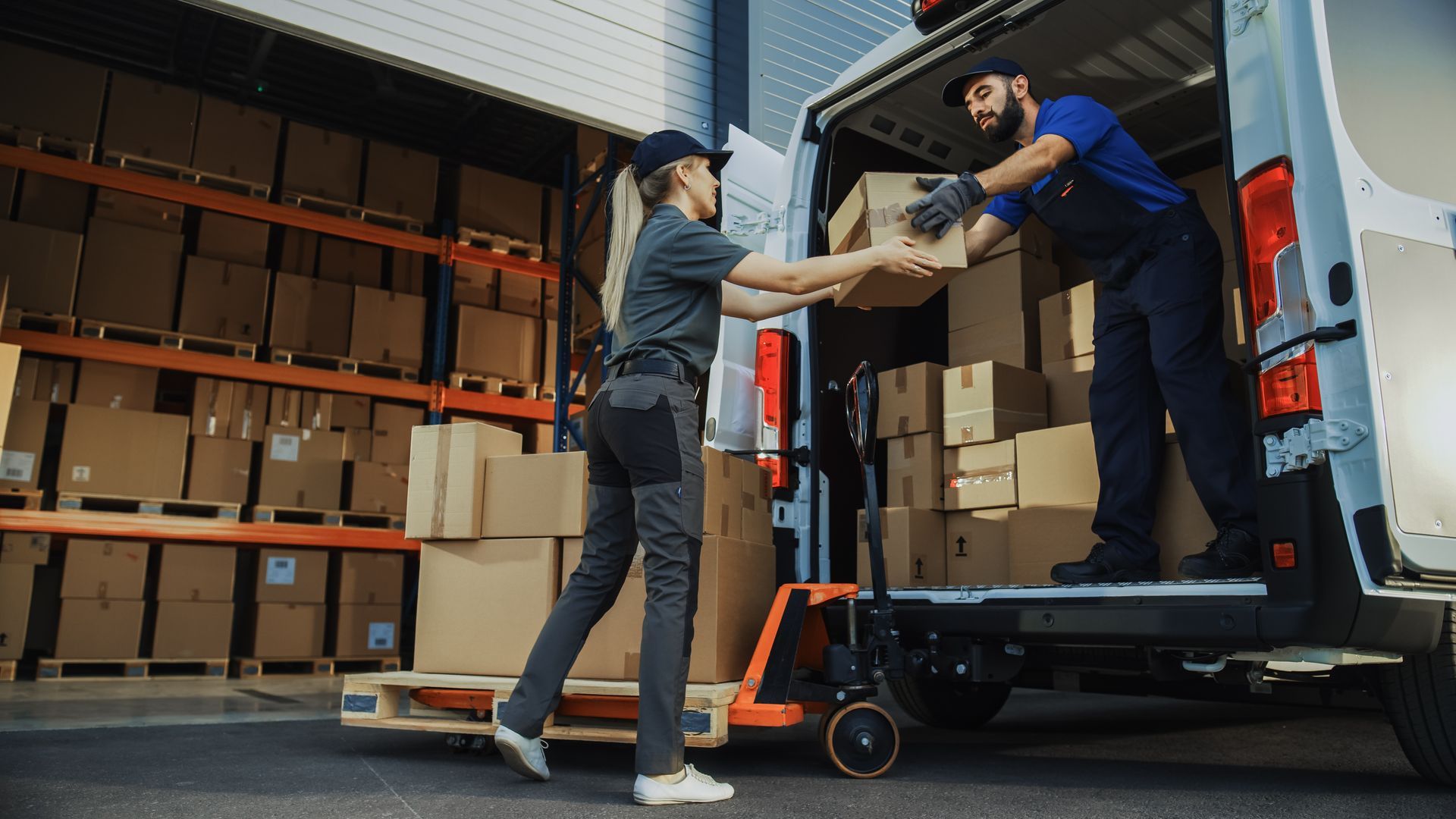 Outside of Logistics Distributions Warehouse: Diverse Team of Workers use Hand Truck Loading Delivery Van with Cardboard Boxes