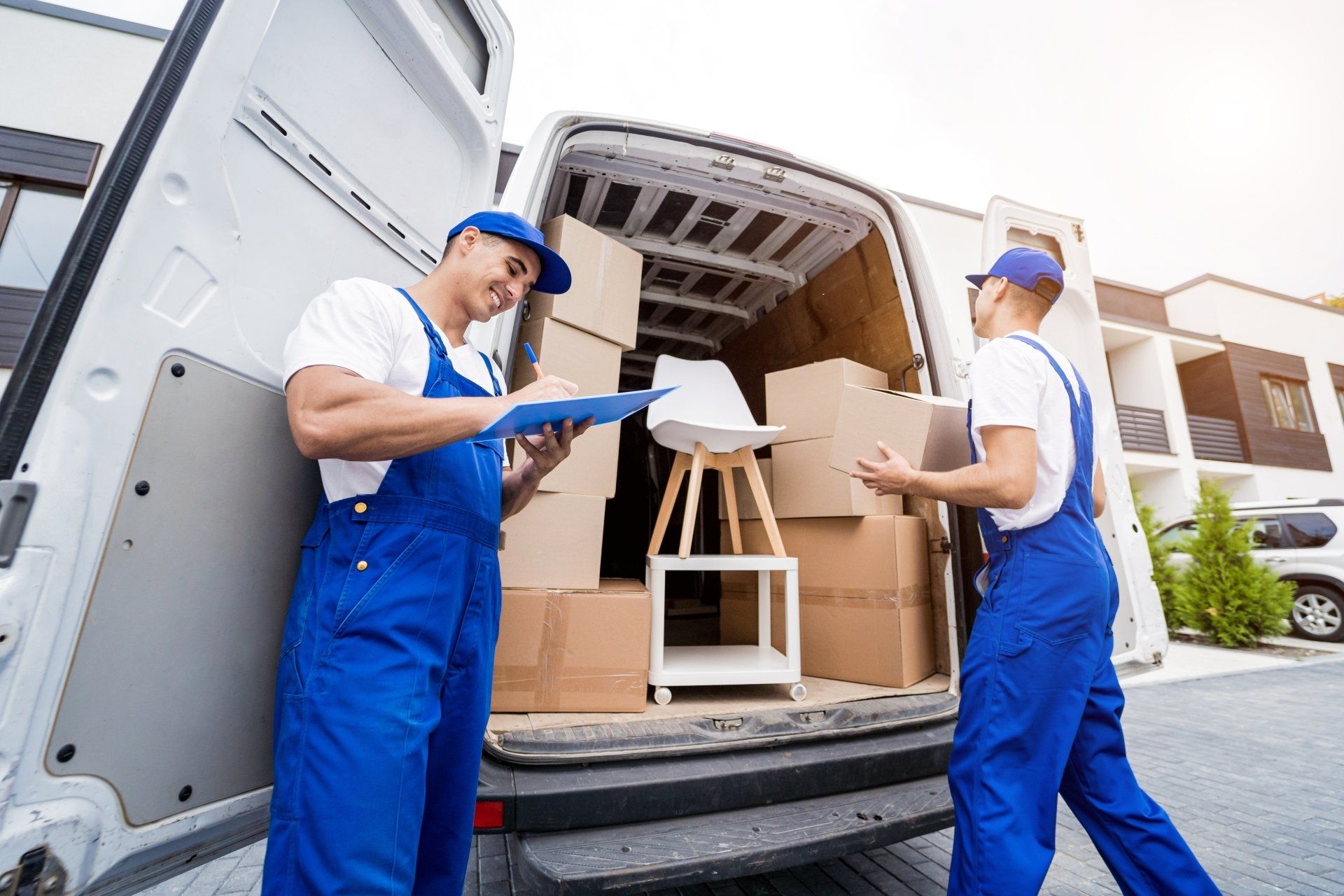 Two removal company workers unloading boxes and furniture from minibus