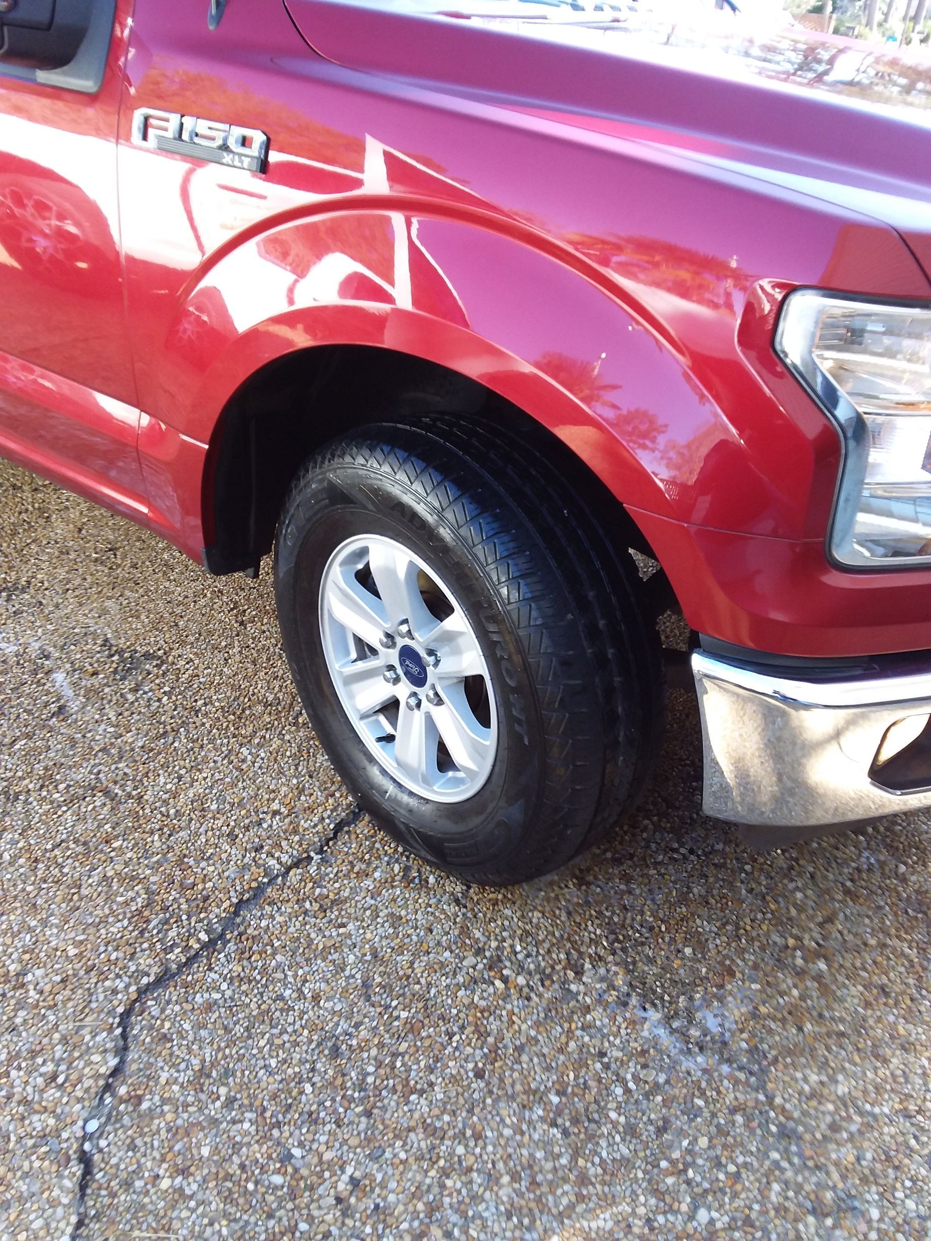 A red ford truck is parked on a gravel road
