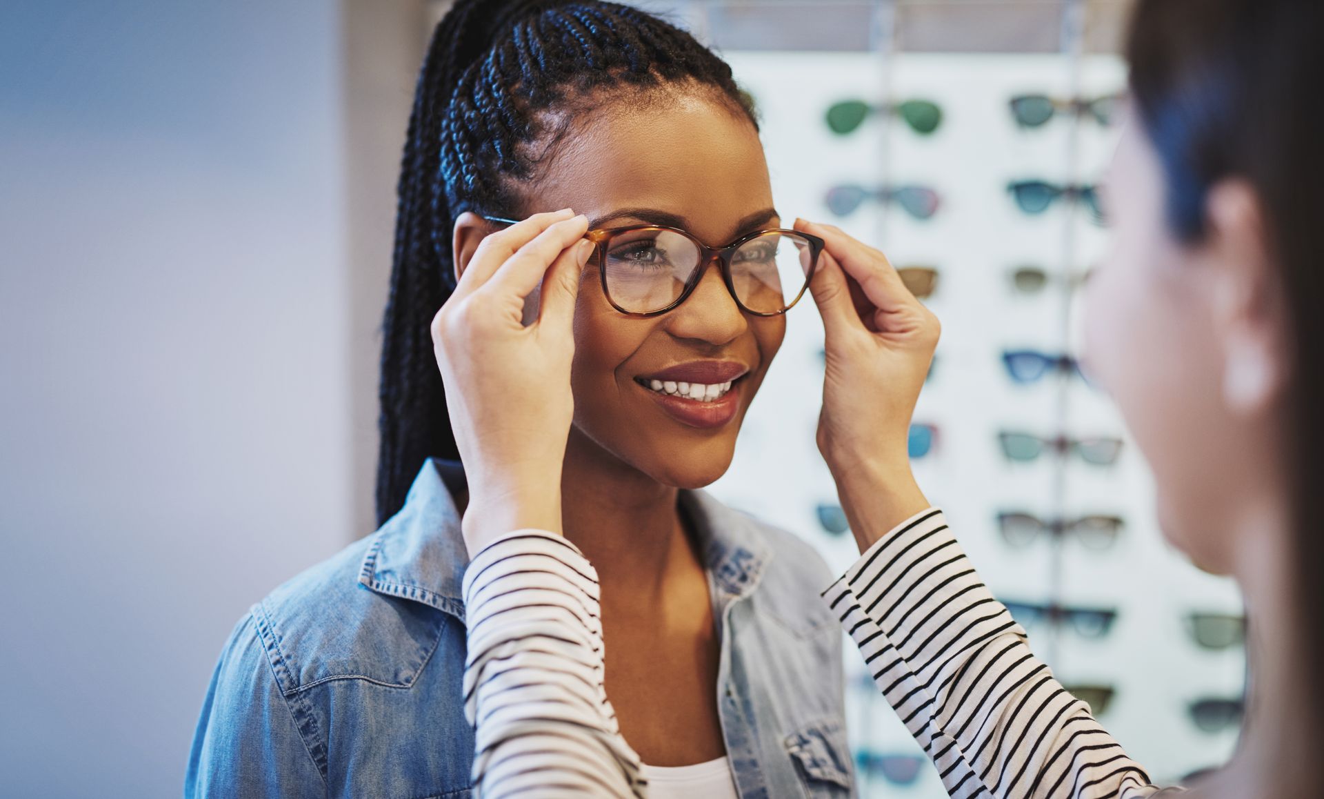 Woman adjusting eyeglasses in a clinic, smiling during an eye exam