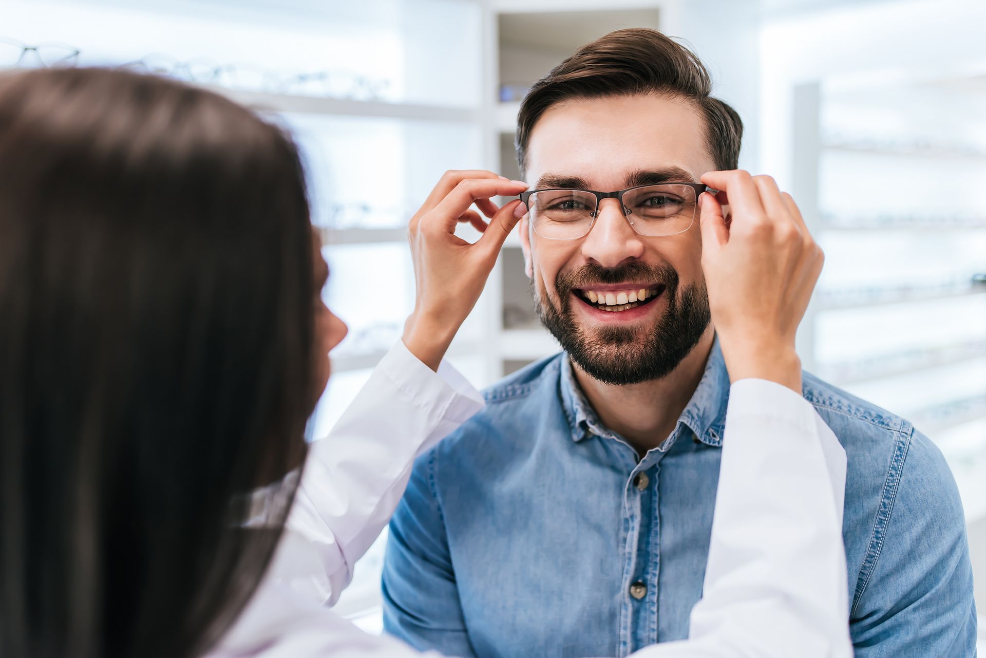 Person adjusting glasses while smiling in a bright office setting