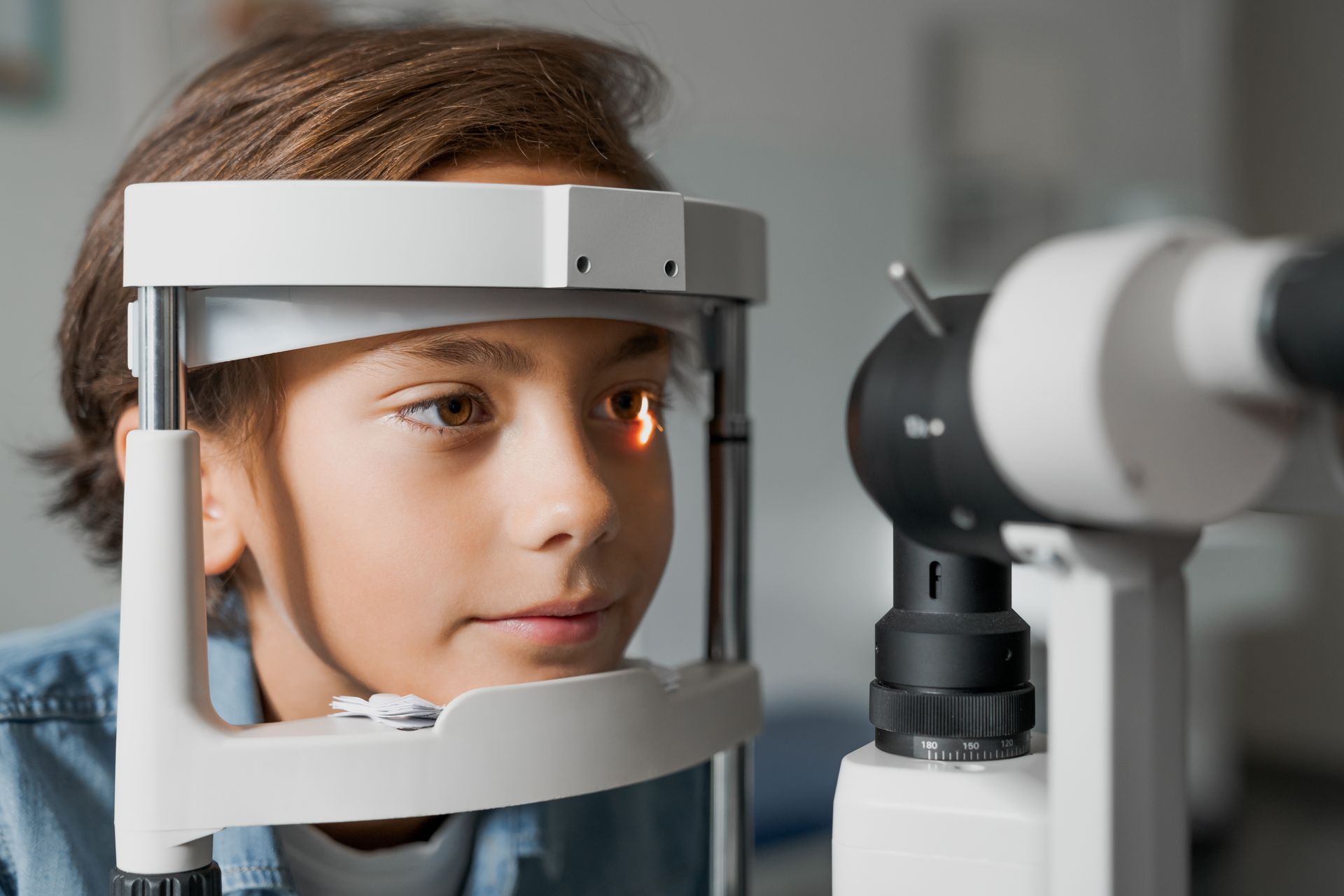 Child in an eye exam machine looking at a vision-testing device