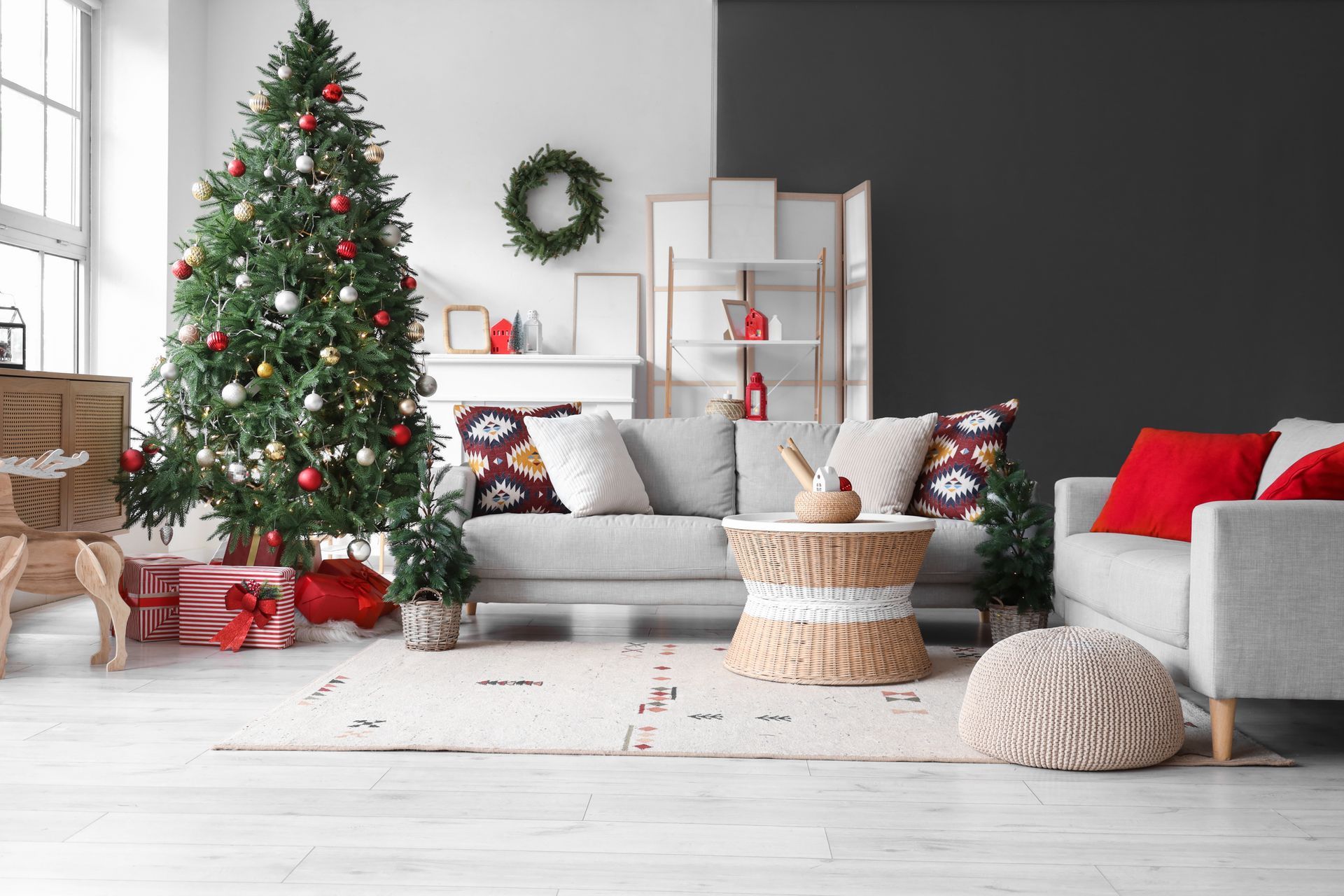Living room decorated for Christmas with a tree, gifts, sofa, rug, and wreath.
