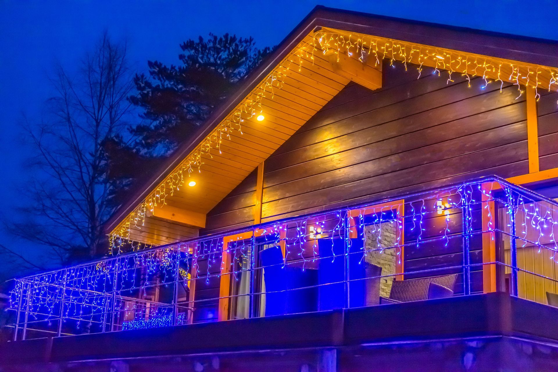 House with blue and yellow Christmas lights at dusk.