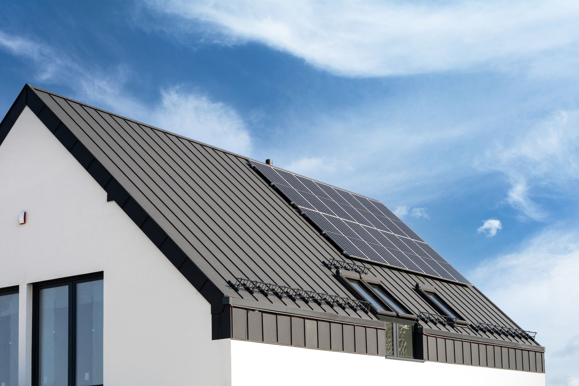 A white house with a black roof and solar panels on it