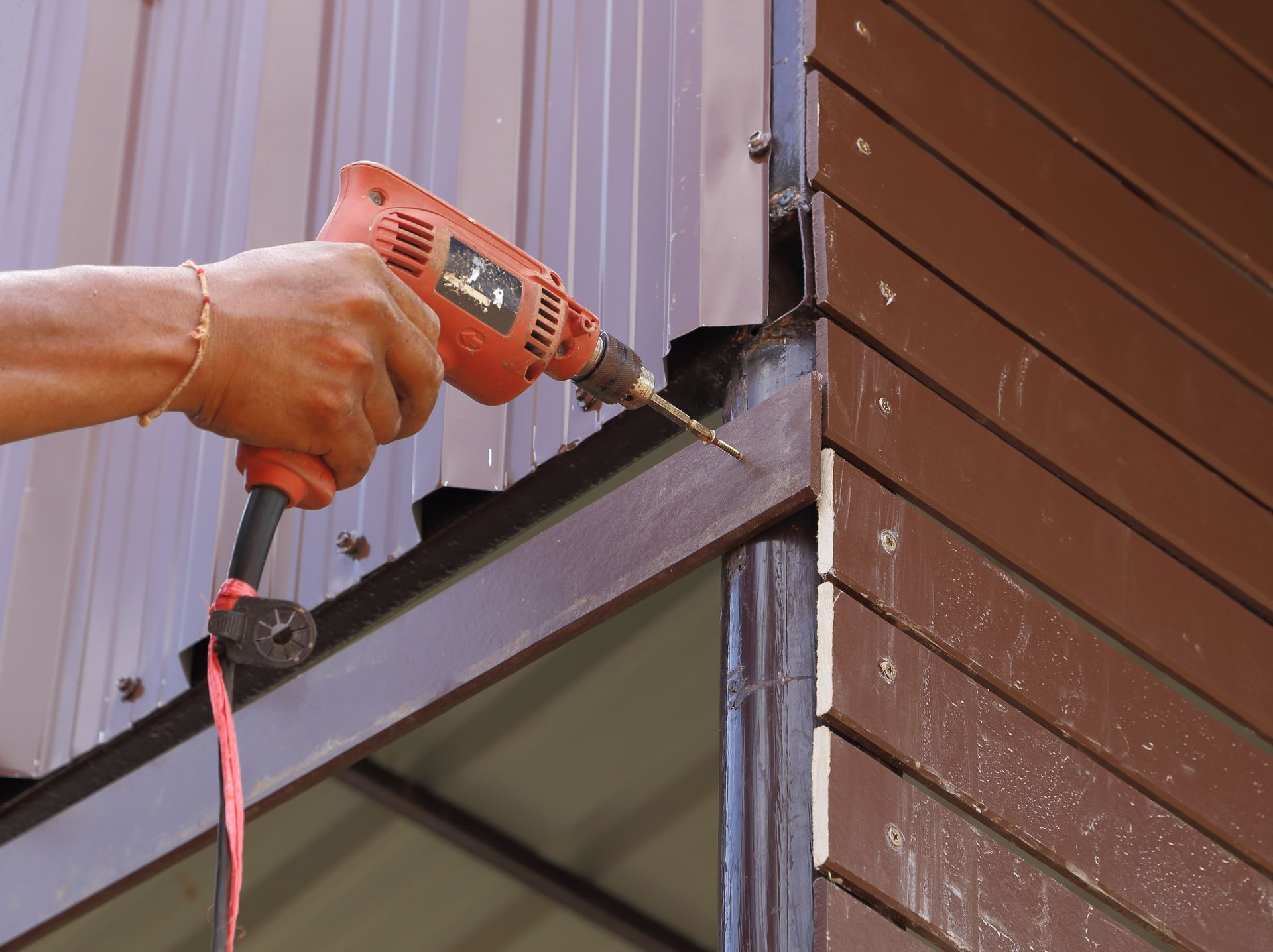 A person is using a drill on a wooden wall