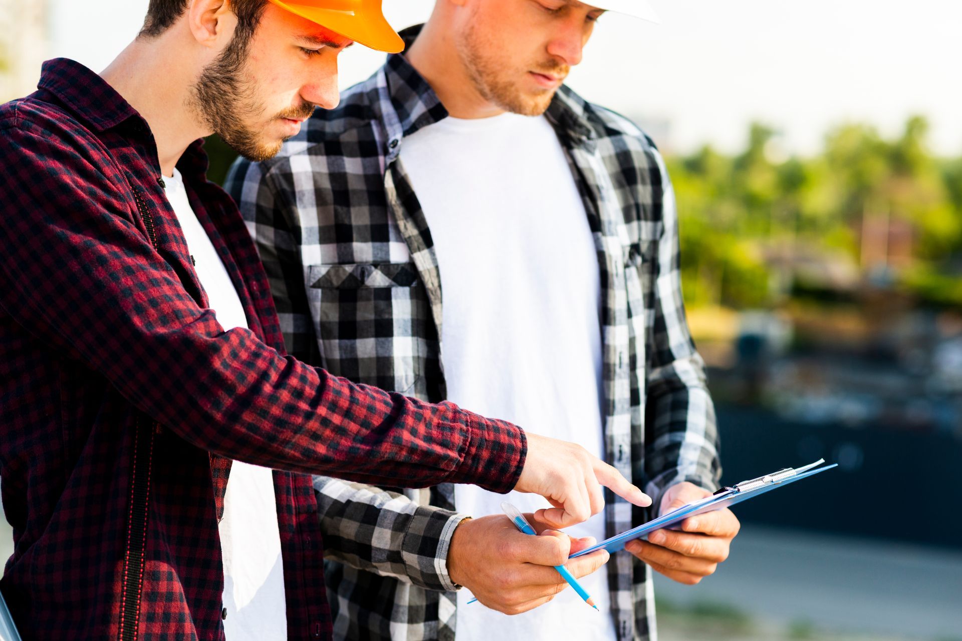 Two construction workers are looking at a clipboard.