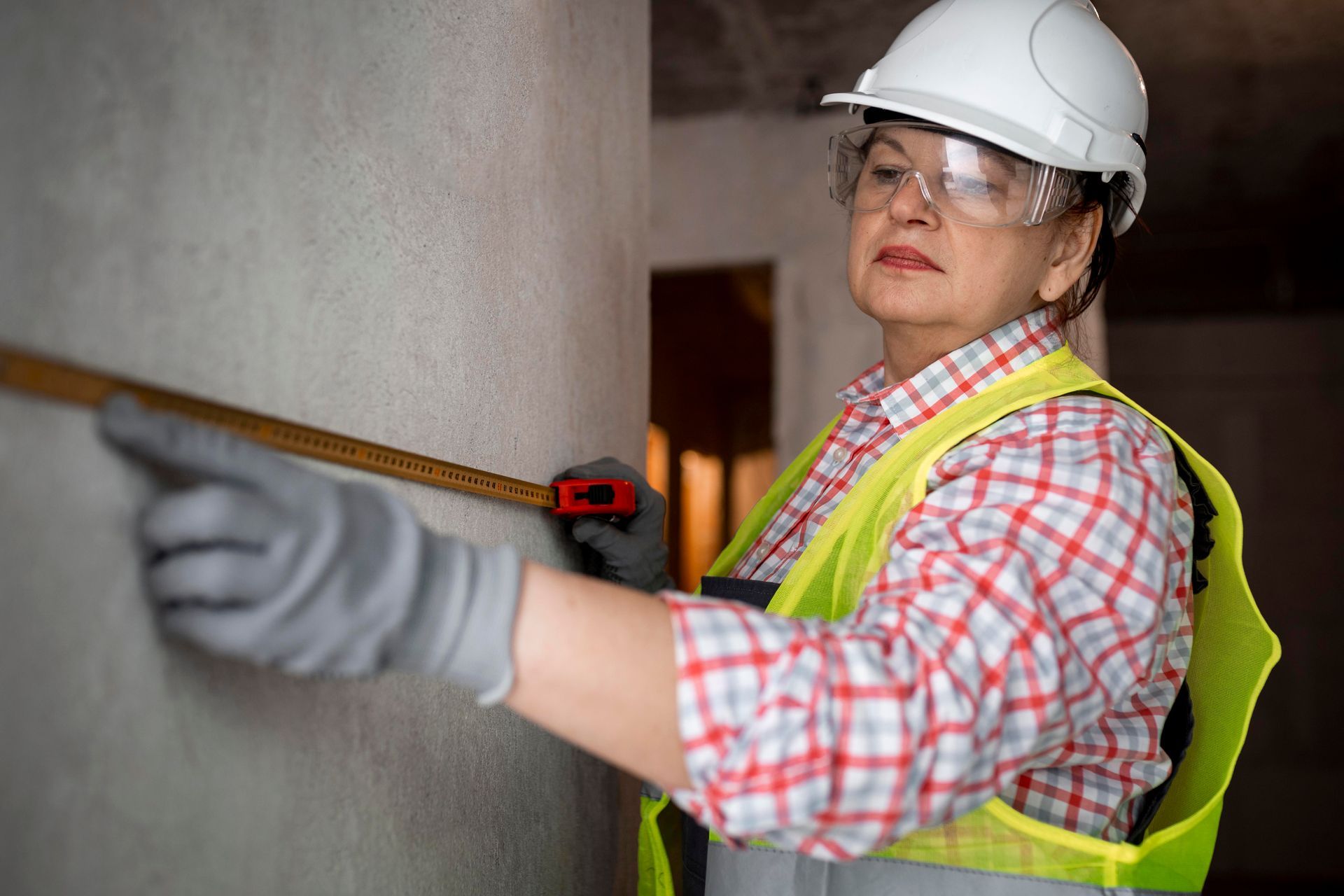 A woman is measuring a wall with a tape measure.