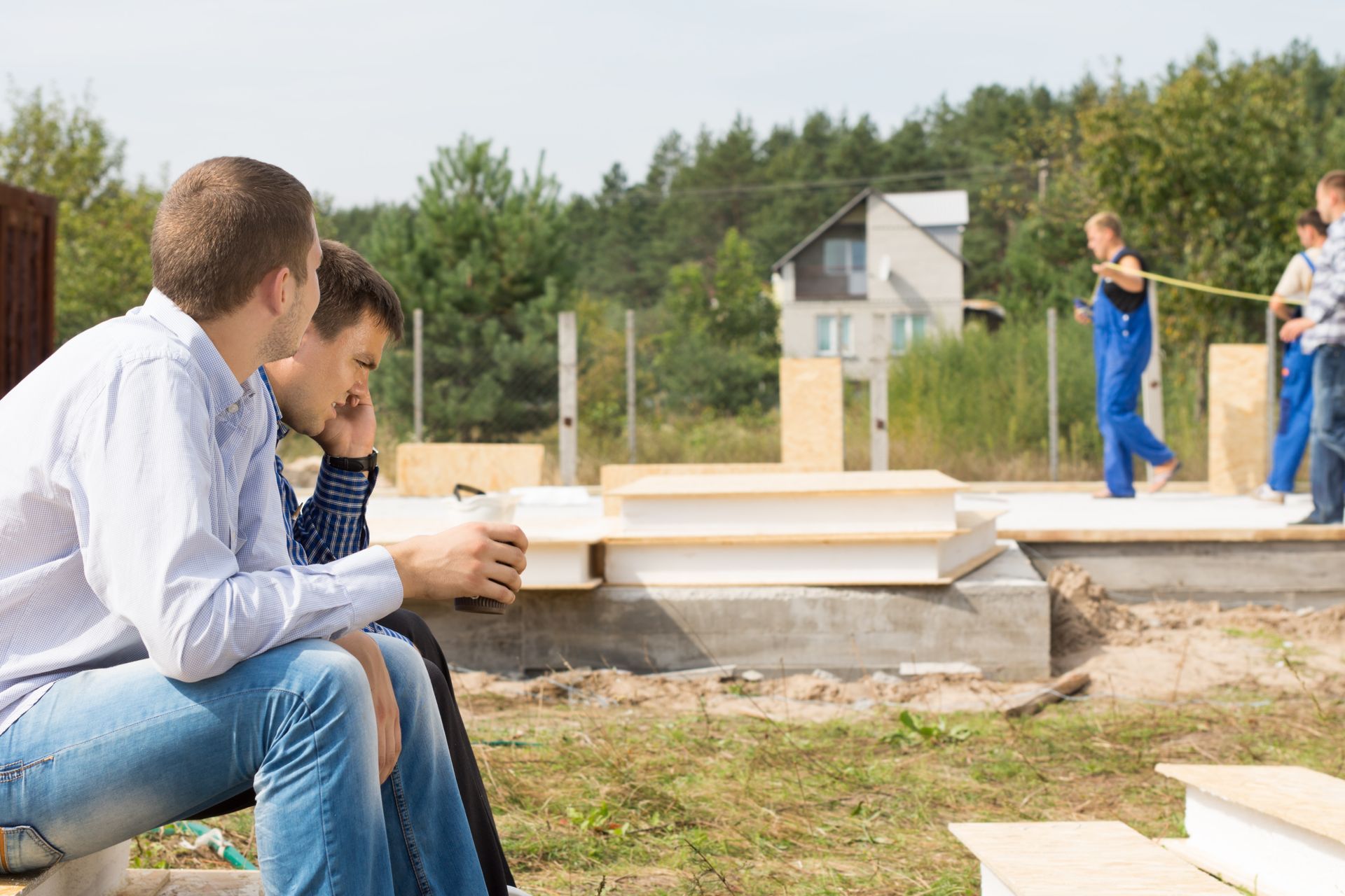A group of men are sitting on a bench in front of a construction site.