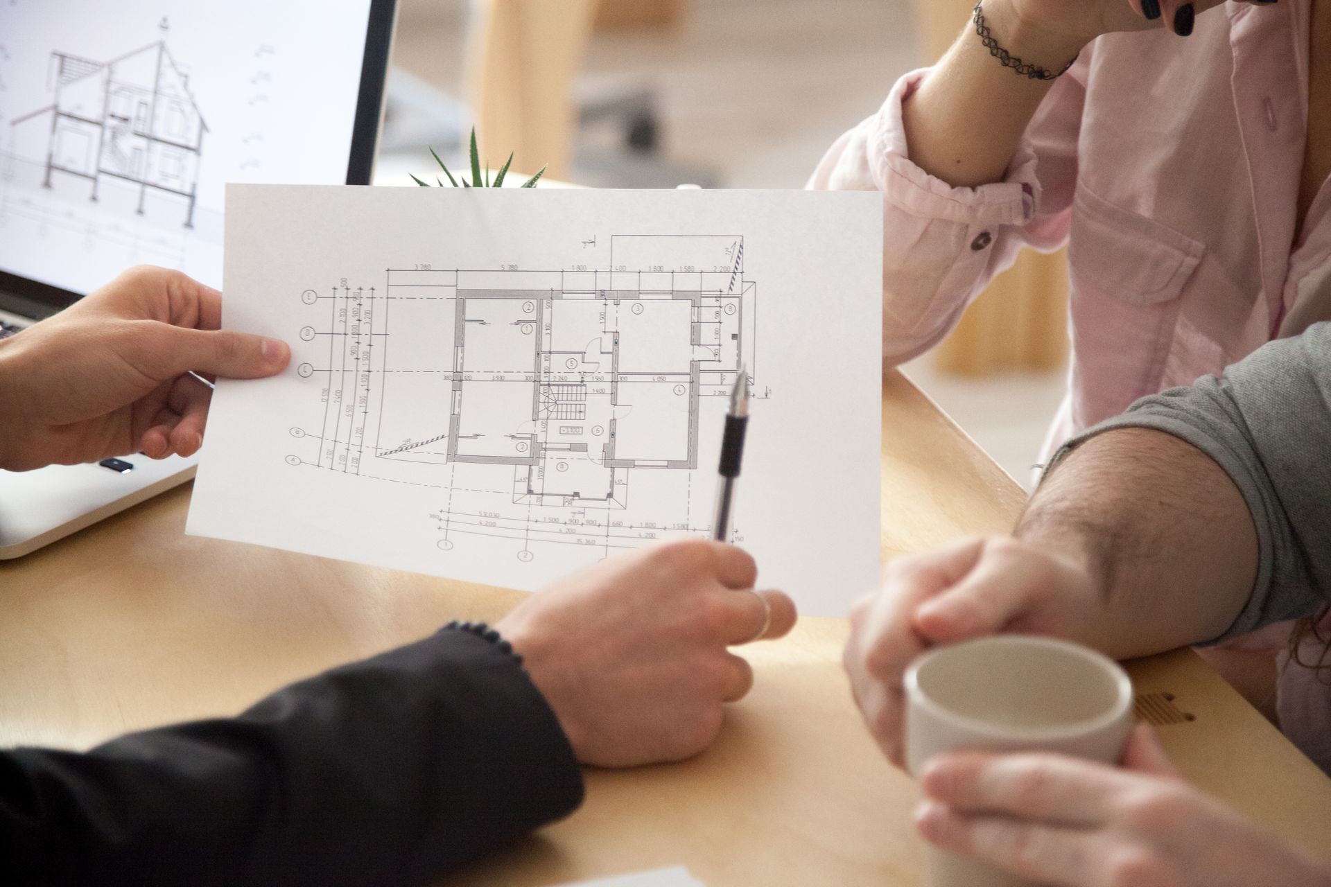 A group of people are sitting at a table looking at a floor plan of a house.