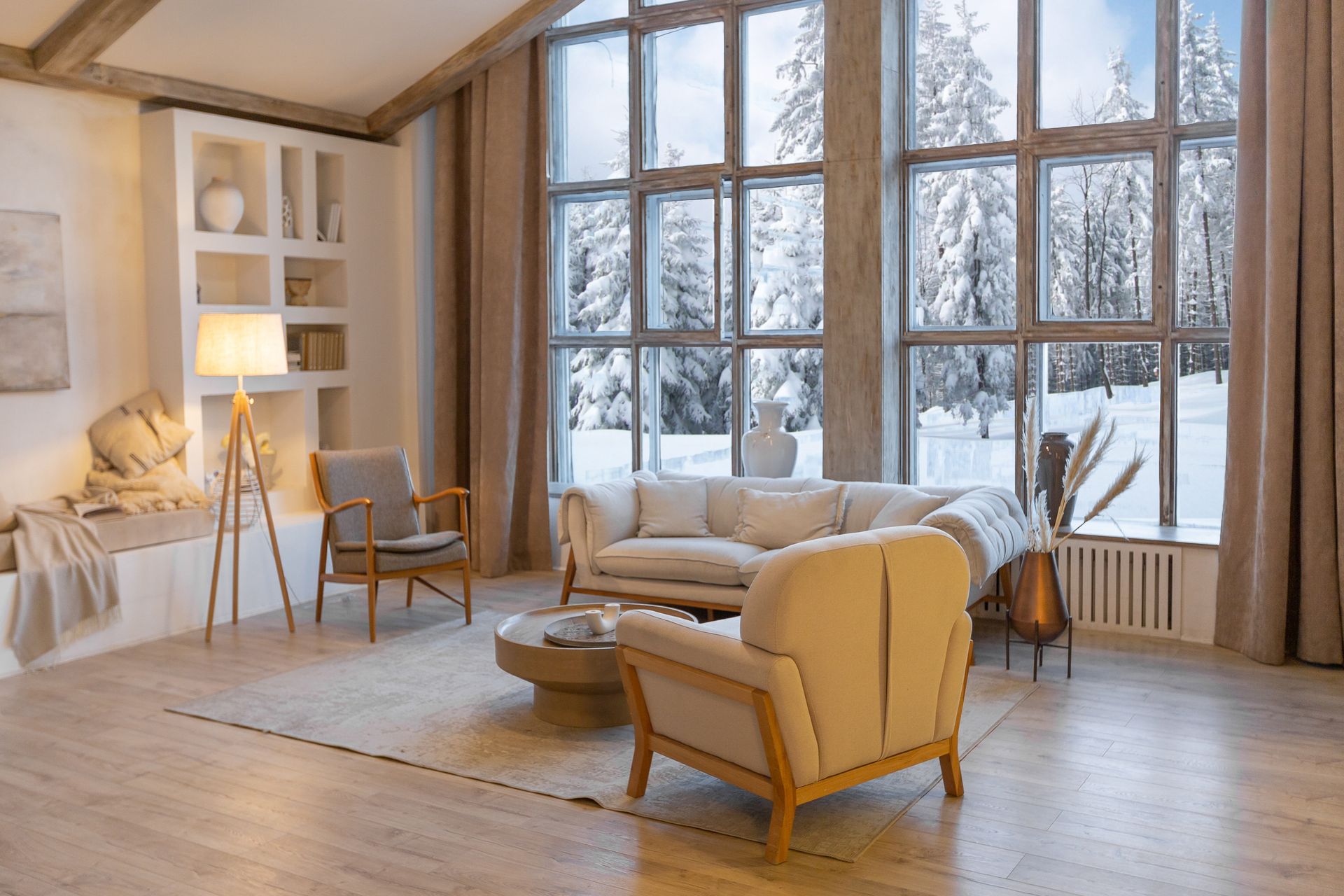 A living room with a couch , chairs , a table and a lot of windows.