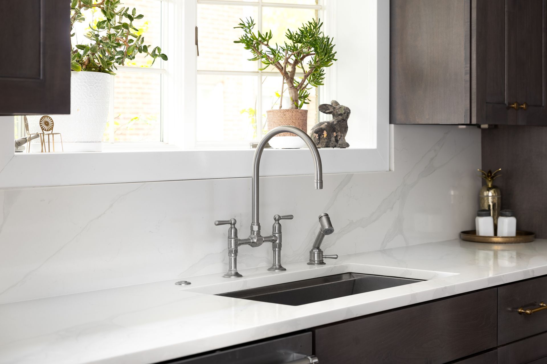 A kitchen sink with a faucet and a window in the background.