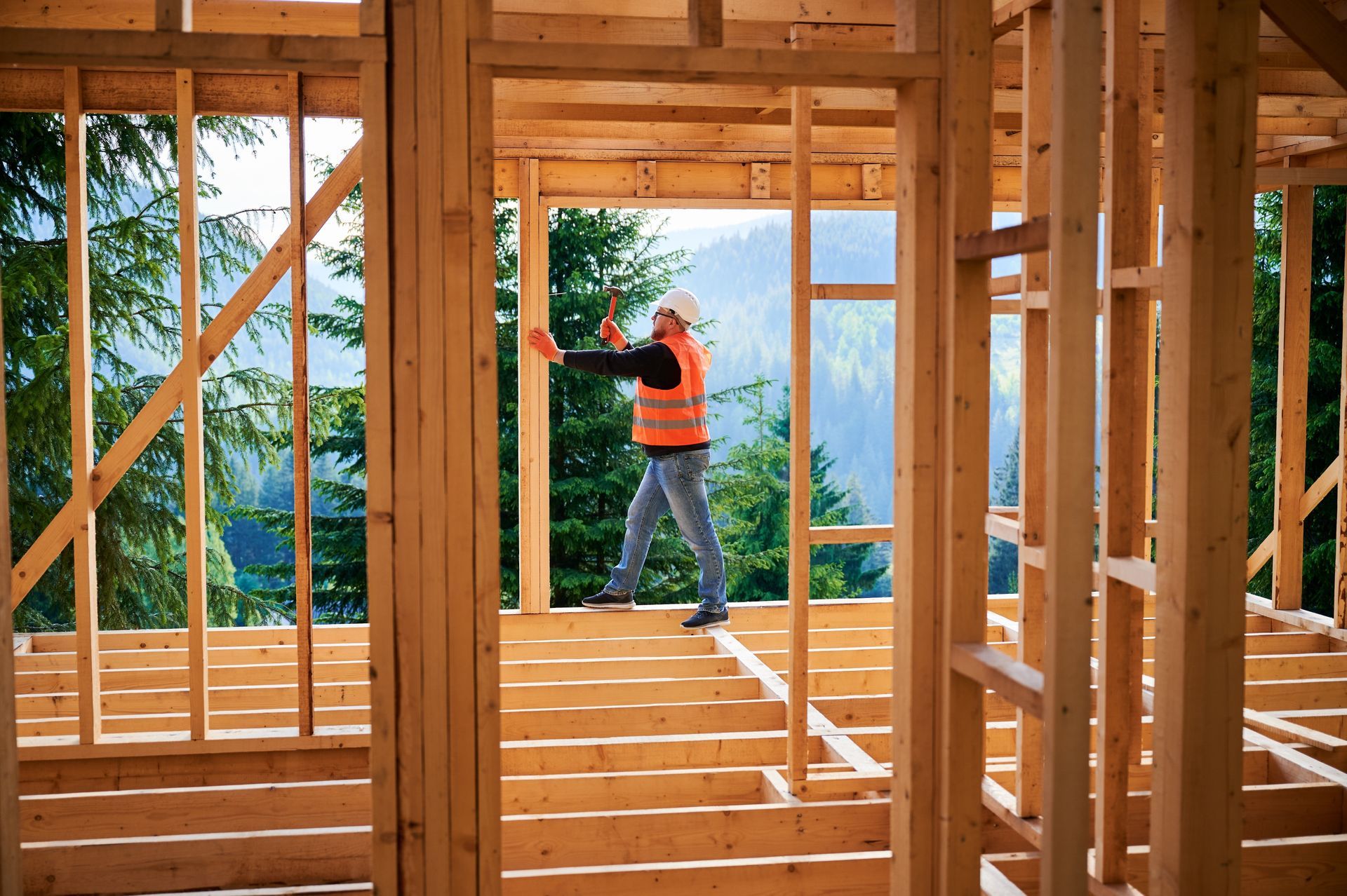 A man is standing in a wooden frame of a house under construction.