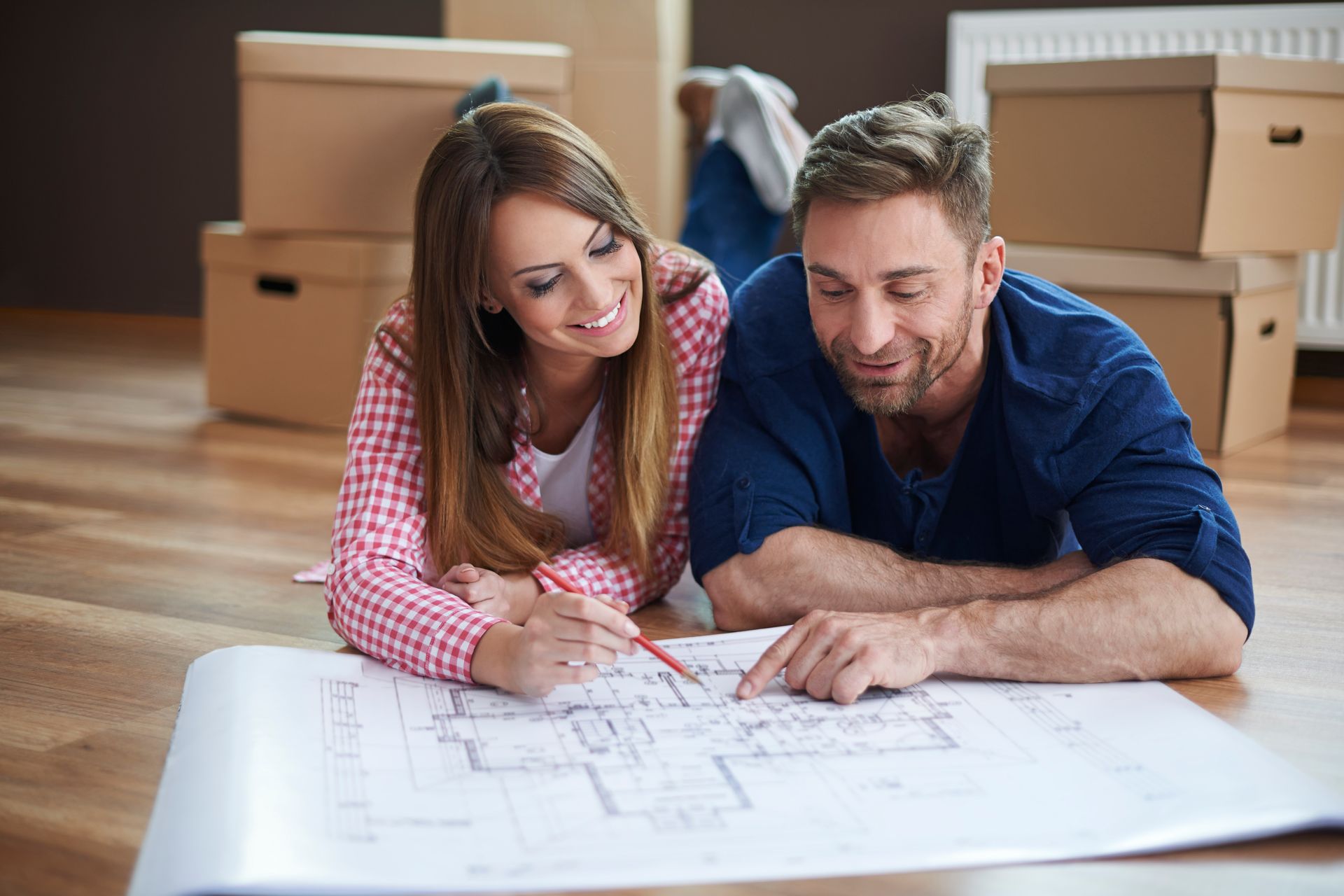 A man and a woman are looking at a blueprint of a house.